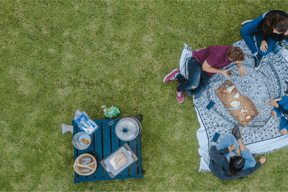 Personas disfrutando de un picnic con una parrilla COBB premier a su lado