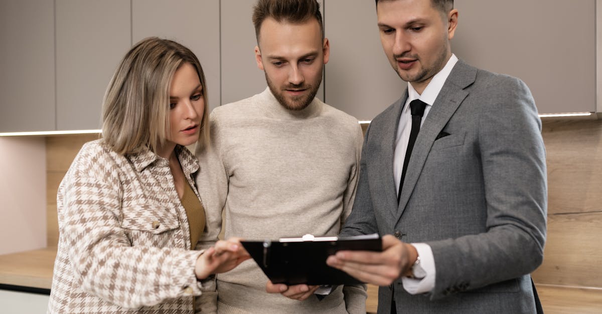 Estate agent presenting property documents on a clipboard to a couple inside a modern apartment