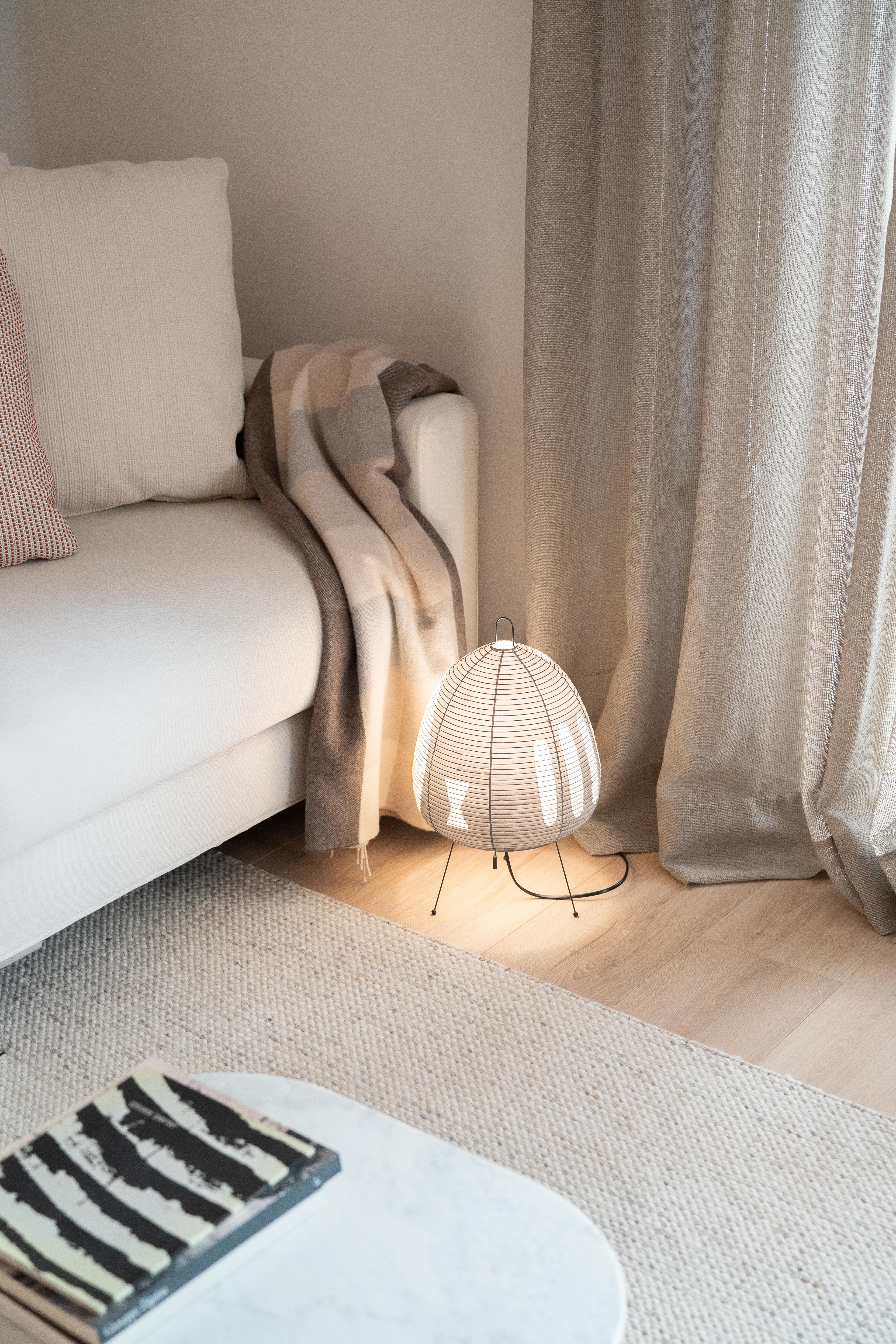 Lámpara de mesa Vitra Akari 1A en el suelo junto a un sofá