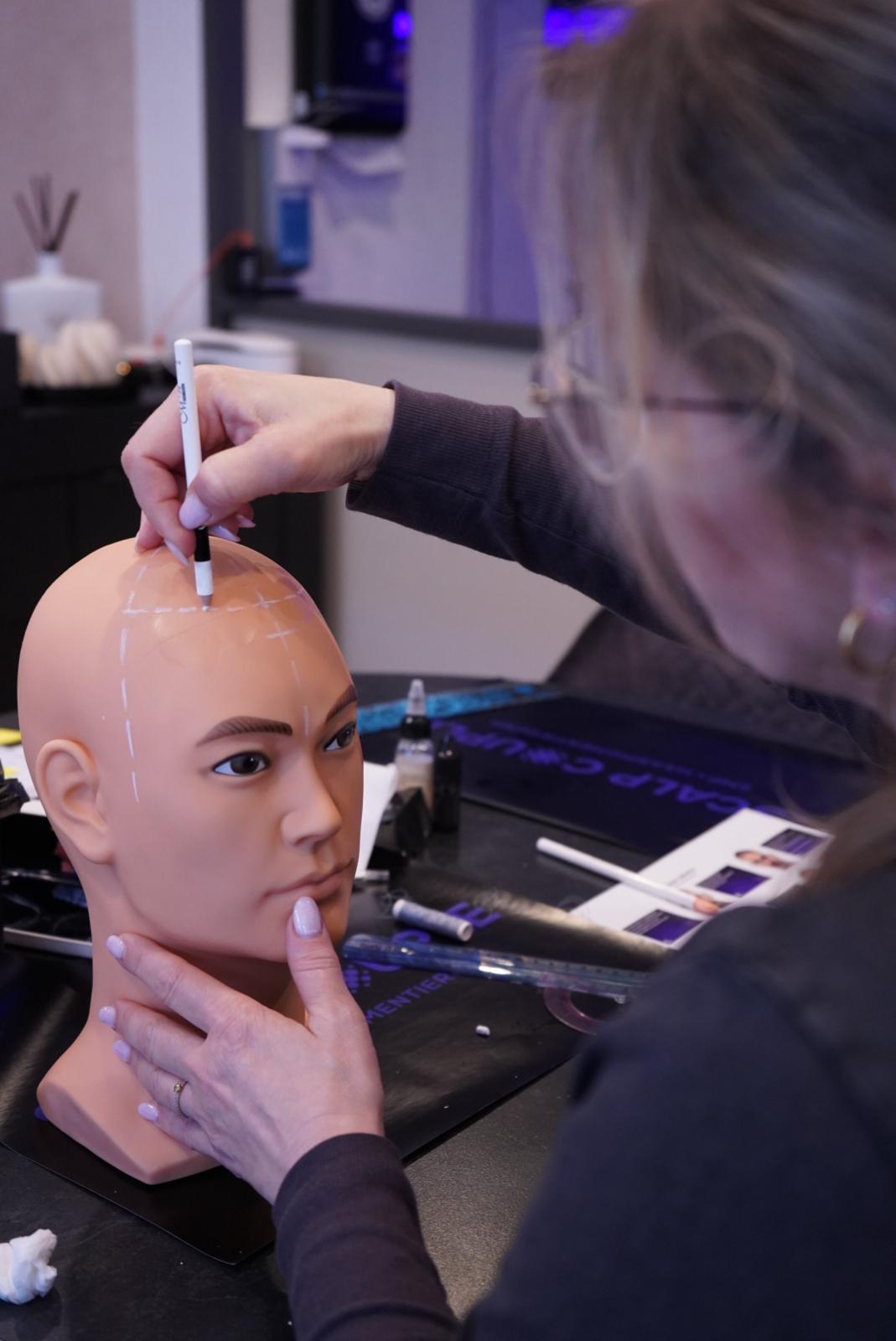 Teilnehmerin der Scalp Couple SMP Akademie zeichnet Haaransatz auf Trainingskopf – Hairline Design in der SMP Ausbildung
