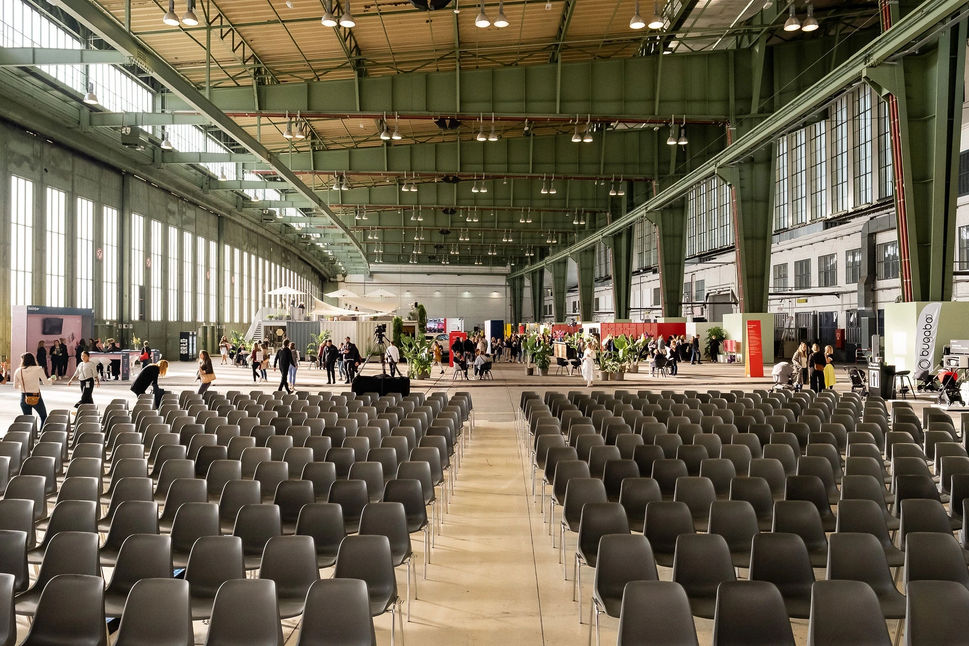 Rows of empty chairs facing the event area in the vast green-steel hangar at Tempelhof before Female Future Force Day opens.