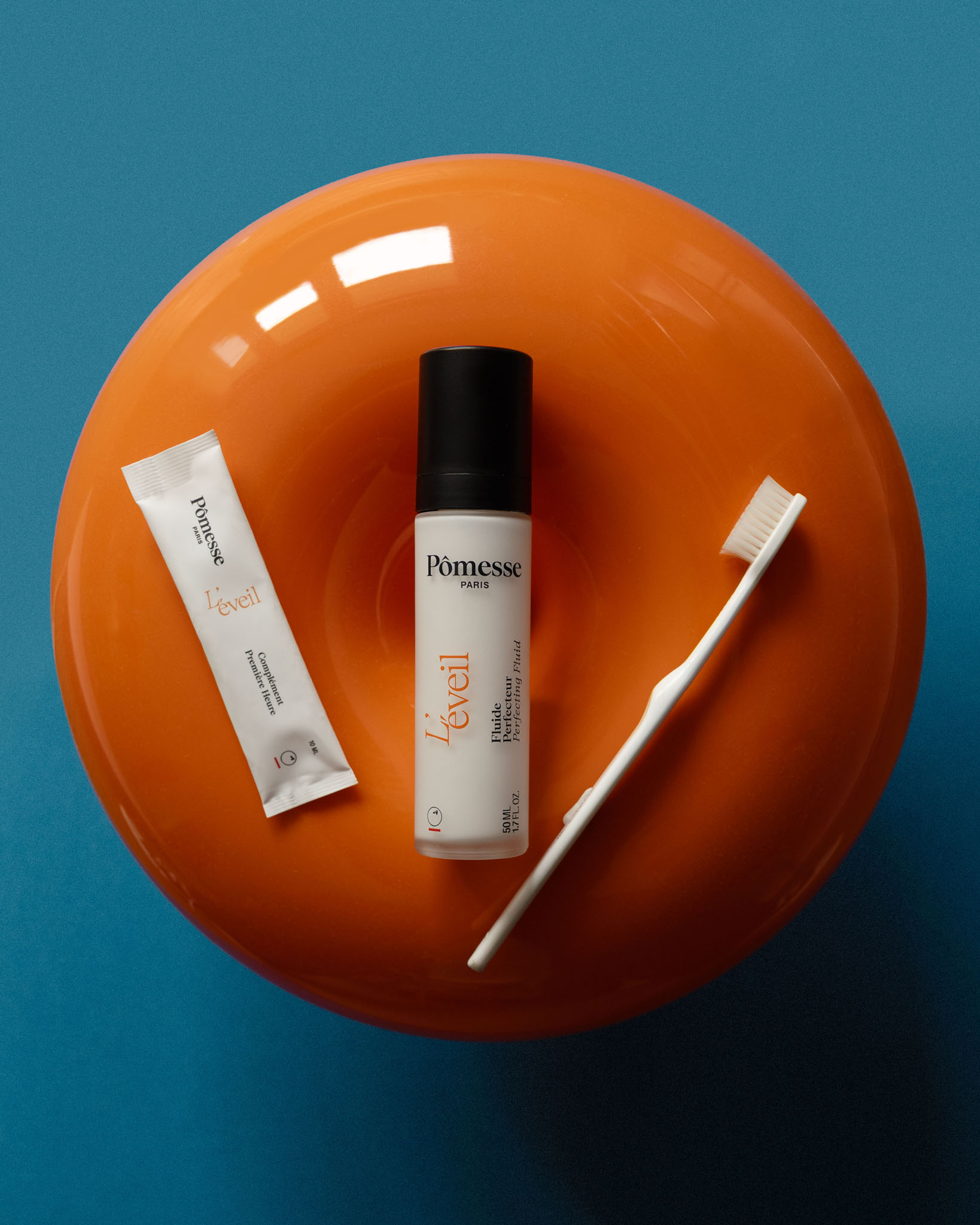 Femme tenant un flacon de soin Pômesse Paris, les yeux fermés, avec une autre femme au premier plan floutée