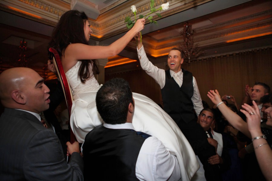 Bride and groom surrounded by friends on a lively wedding dance floor