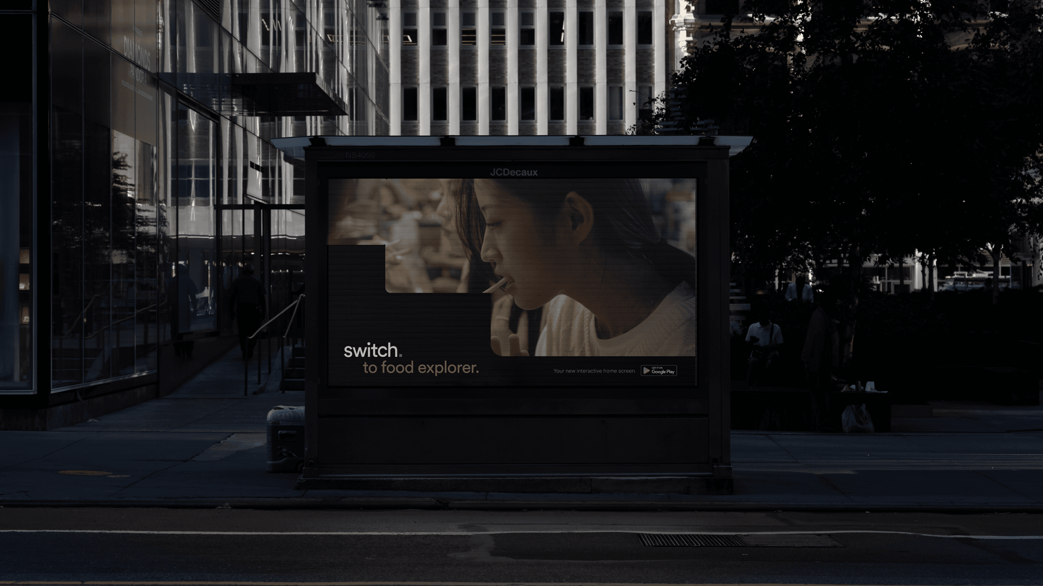 A dark advertisement on a digital billboard displays a woman in profile, smoking a cigarette, with the text "switch to food explorer." Below the ad, the text "your next homebreaker starts @giphy" is visible. The billboard is mounted on a pole on a sidewalk beside a street, with buildings and a tree in the background.