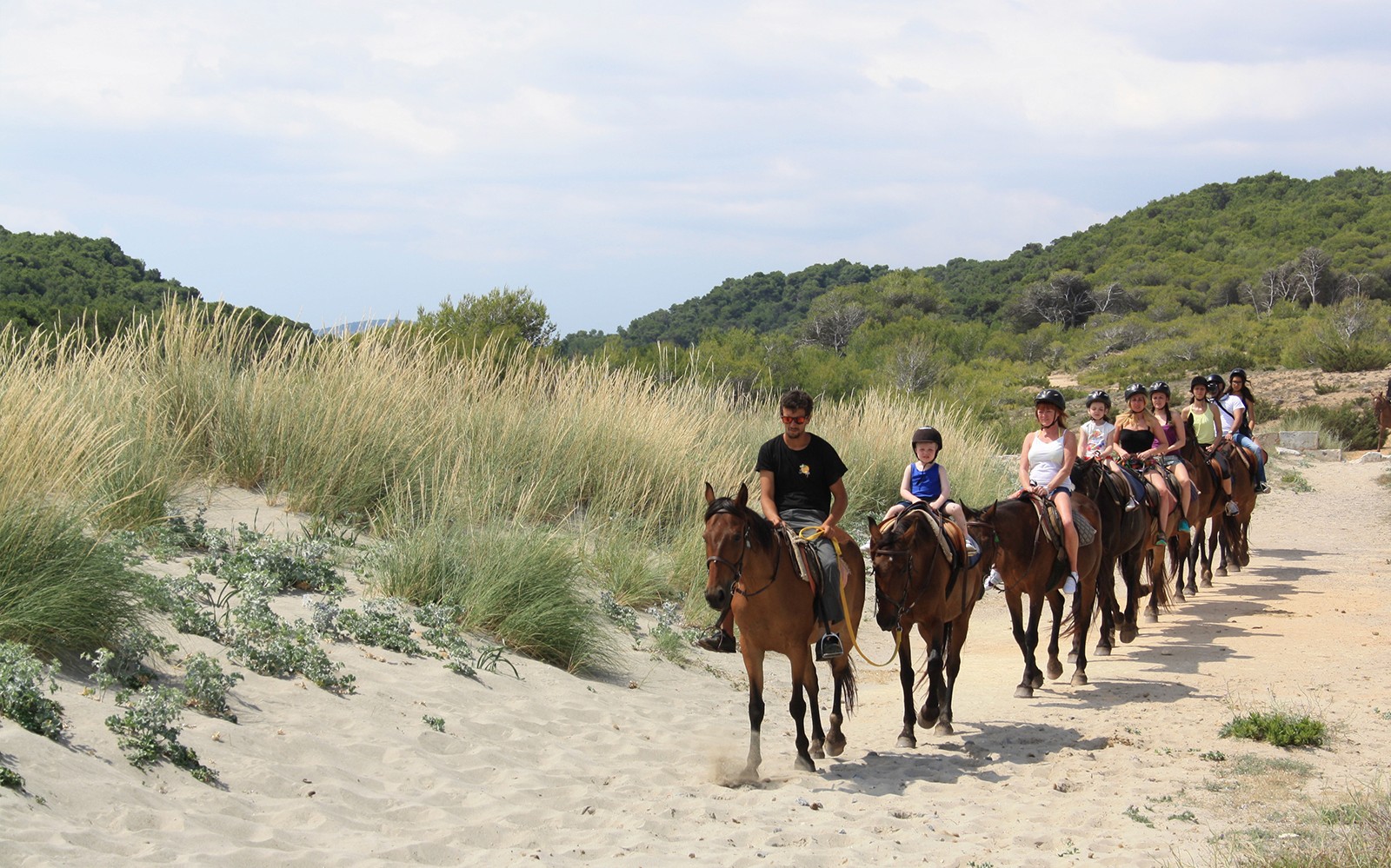 Paseo a caballo en grupo por un sendero de playa arenosa en Mallorca.