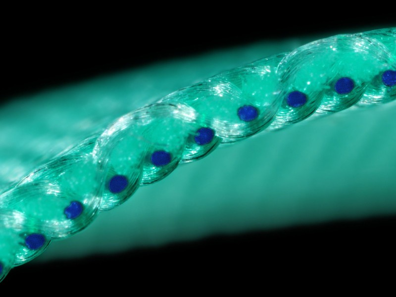 A close-up image of a turquoise beaded string with dark blue accents against a dark background.