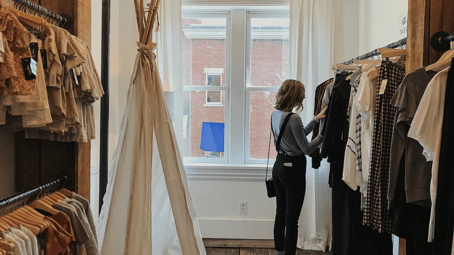 A woman browses through clothing hanging on a rack in a store