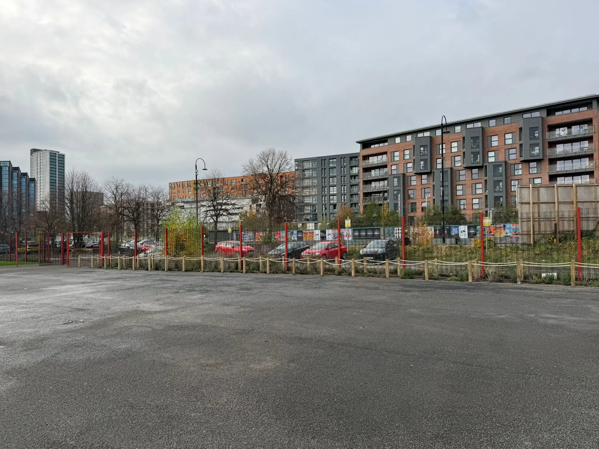 A view of a parking lot with buildings and trees in the background under a cloudy sky.