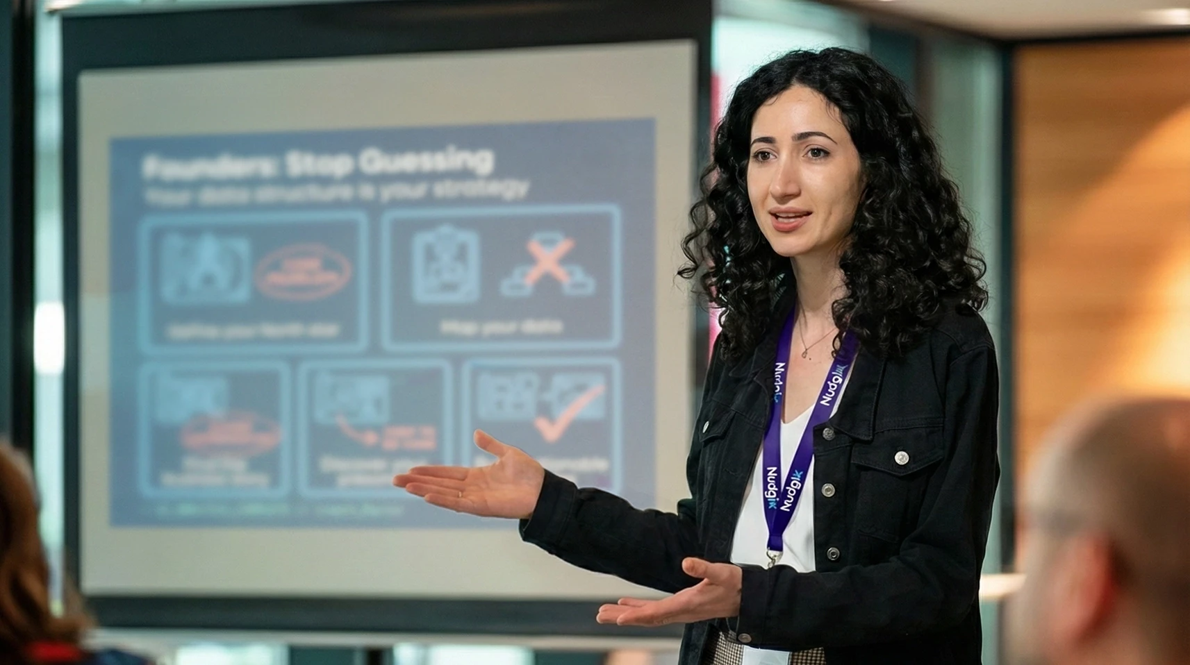 Product design strategist presenting to founders on how to transform complex technology into an investable asset for pre-seed and seed fundraising. The presentation slide, titled 'Founders: Stop Guessing,' focuses on defining a north star and mapping data to improve UX/UI strategy and prepare the MVP for investors