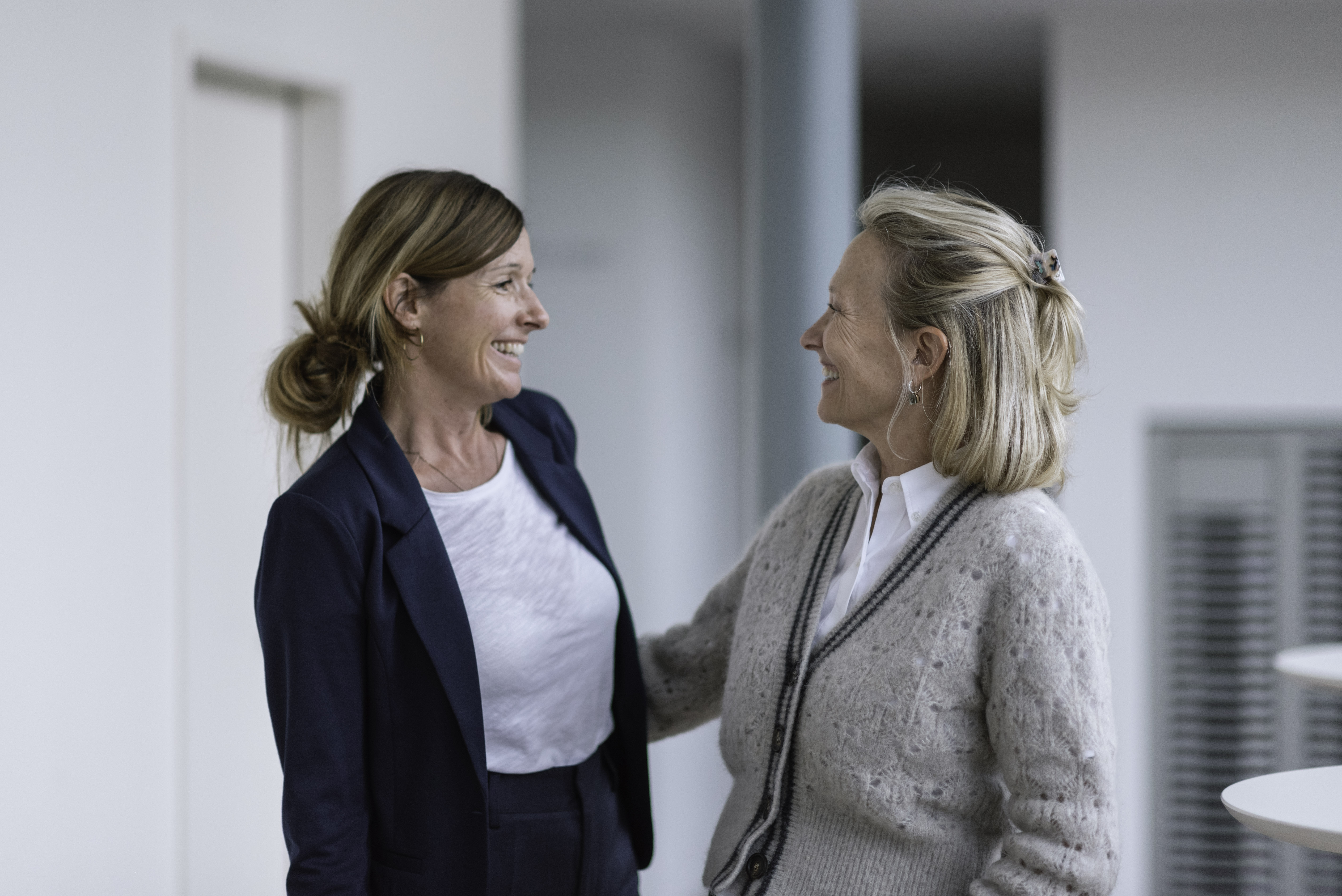 Freundliche Interaktion zwischen zwei Frauen aus dem Team, die die unterstützende und einladende Atmosphäre festhält.