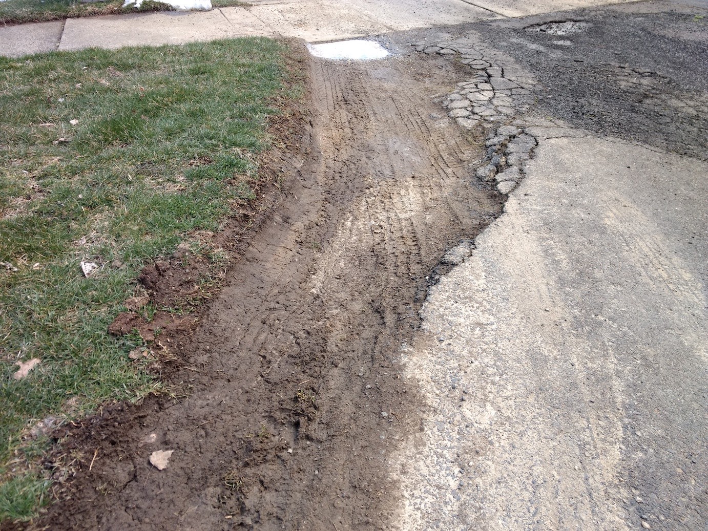 Gravel driveway showing ruts and erosion caused by poor drainage and base failure.