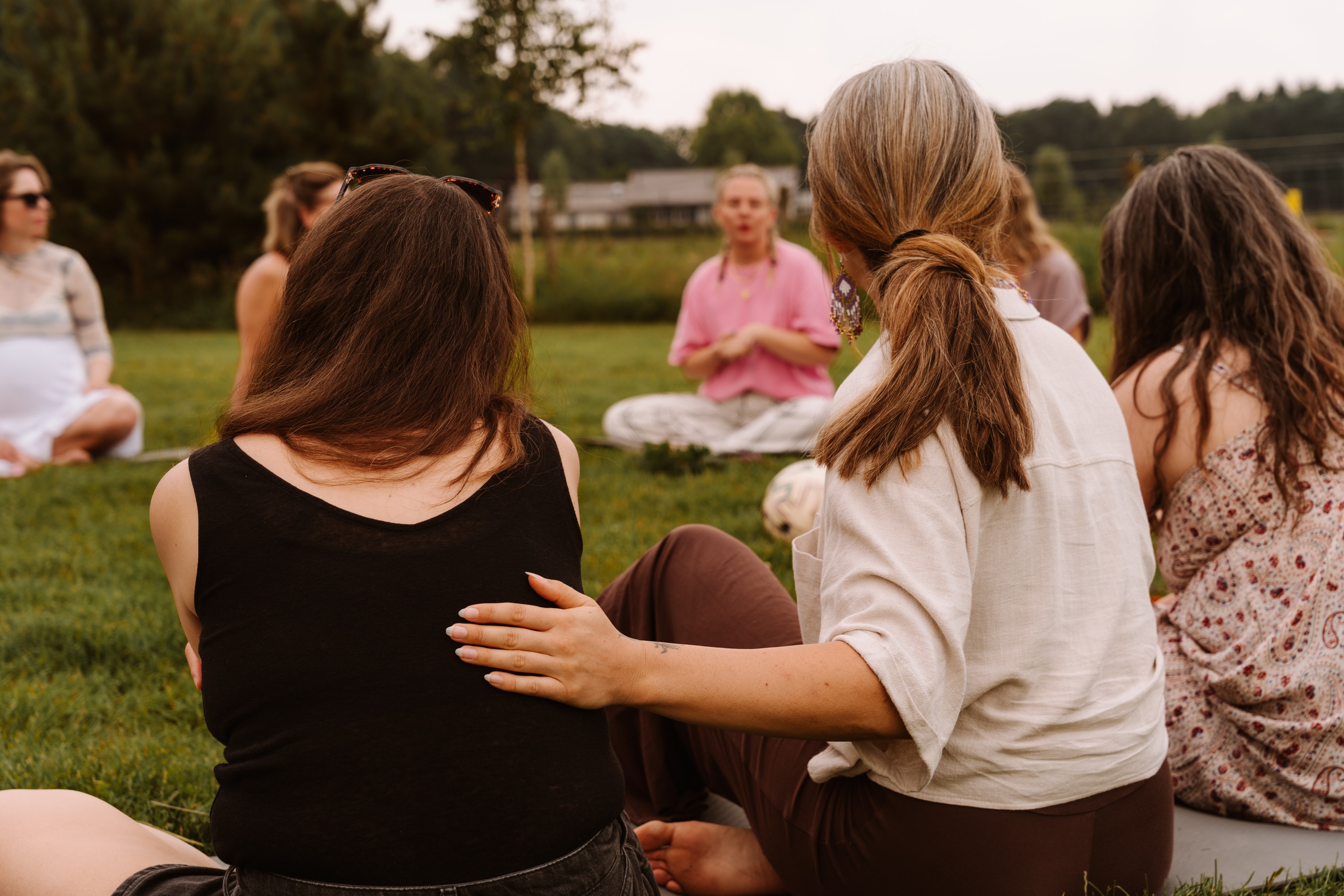 Drie vrouwen in gesprek in het gras, lachend