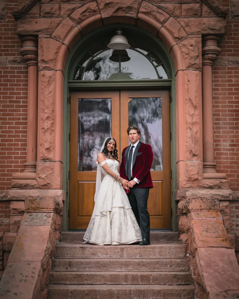 Newlyweds standing on the steps of a brick building