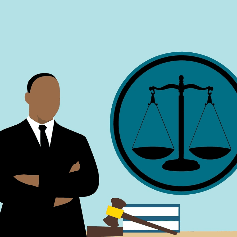 A man standing with his arms crossed in front of a gavel, some books, and a seal of justice on the wall. 