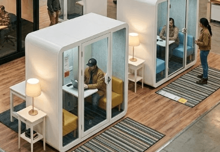 Modern interior space with a blue circular coffee table, flowers in a vase, and books neatly arranged.