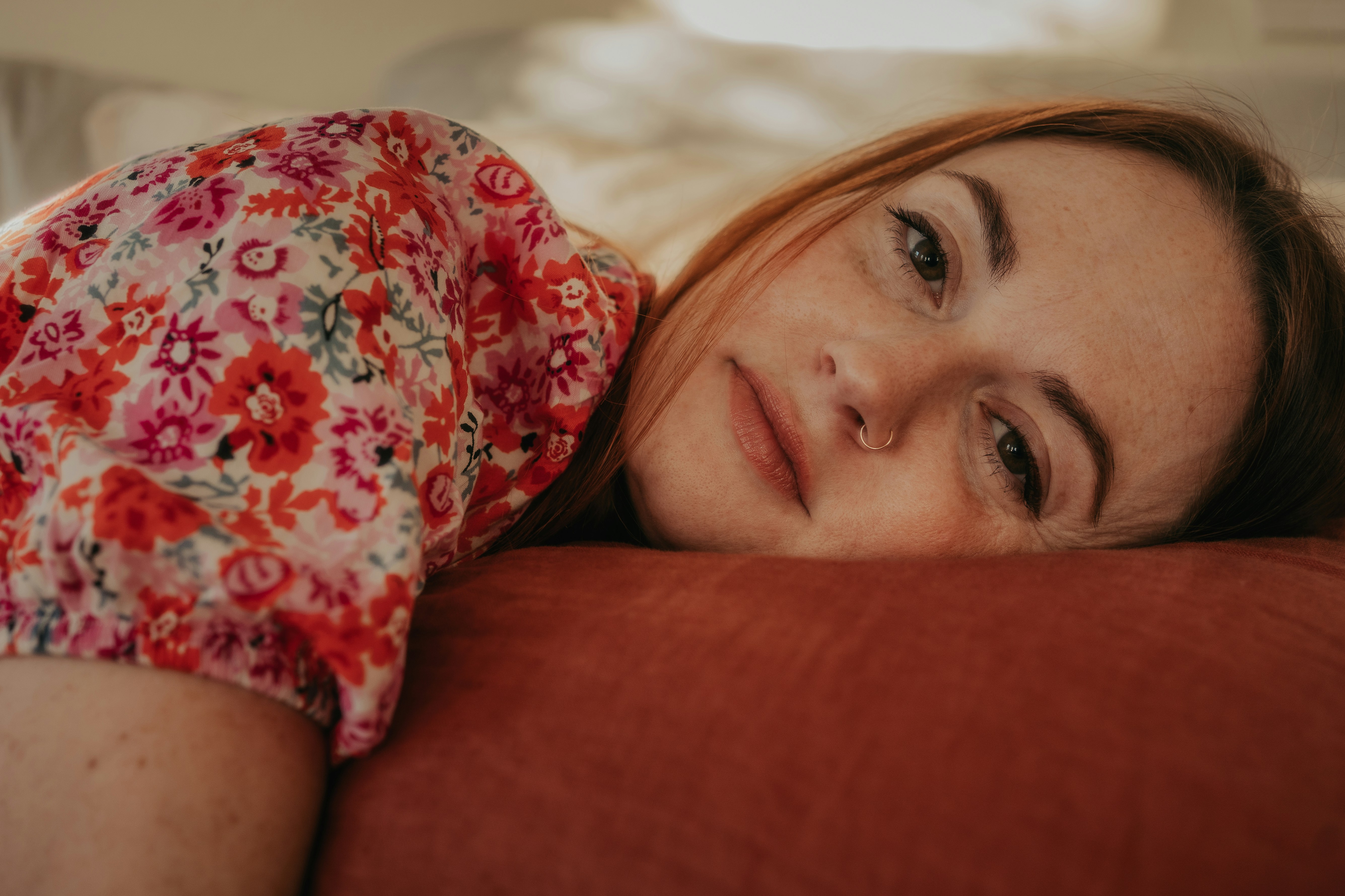 woman in red and white floral shirt lying on brown couch