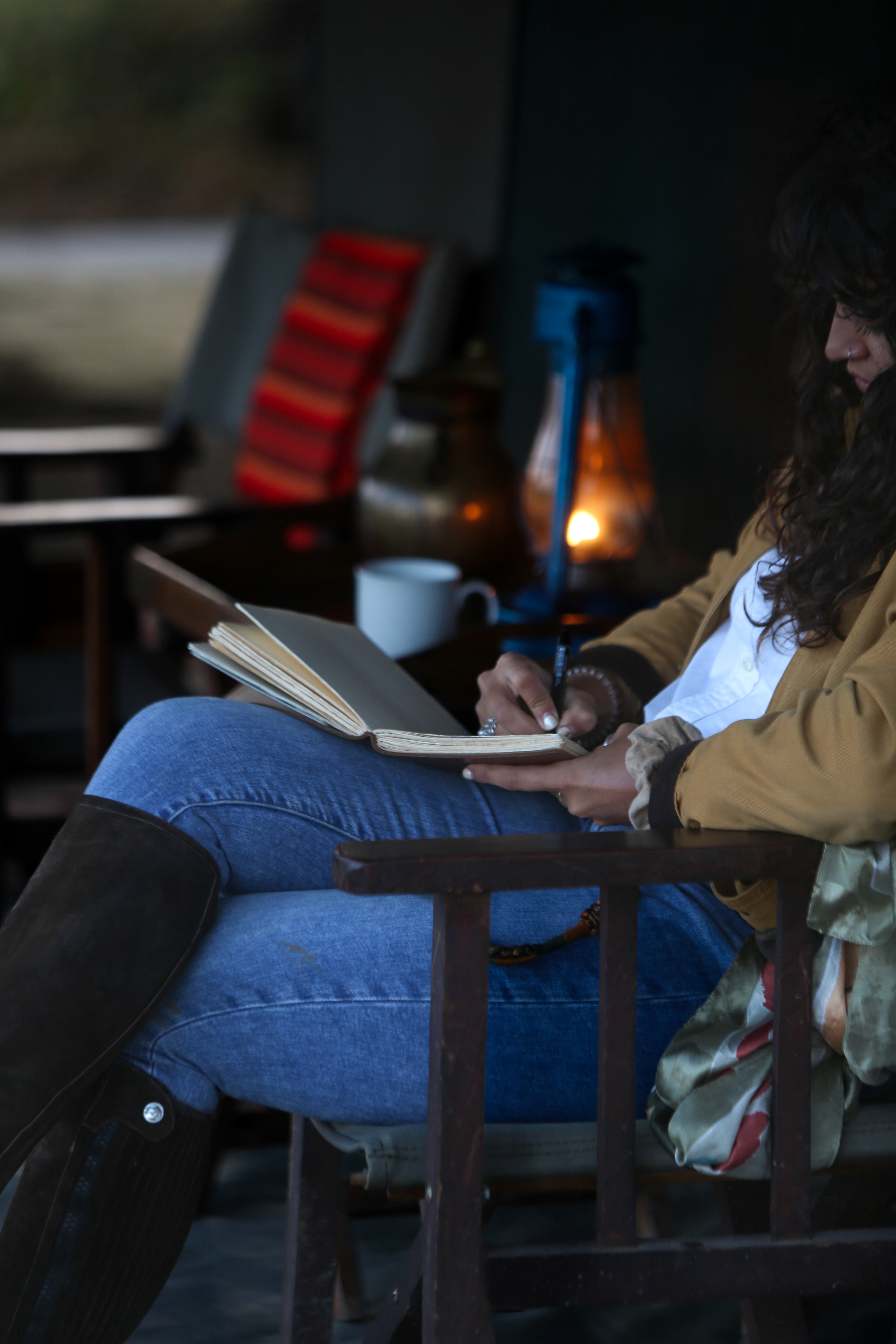 Kilimanjaro Elephant Ride, Arusha, Tanzania. En kvinna sitter och läser utanför ett tält uppsatt i vildmarken.