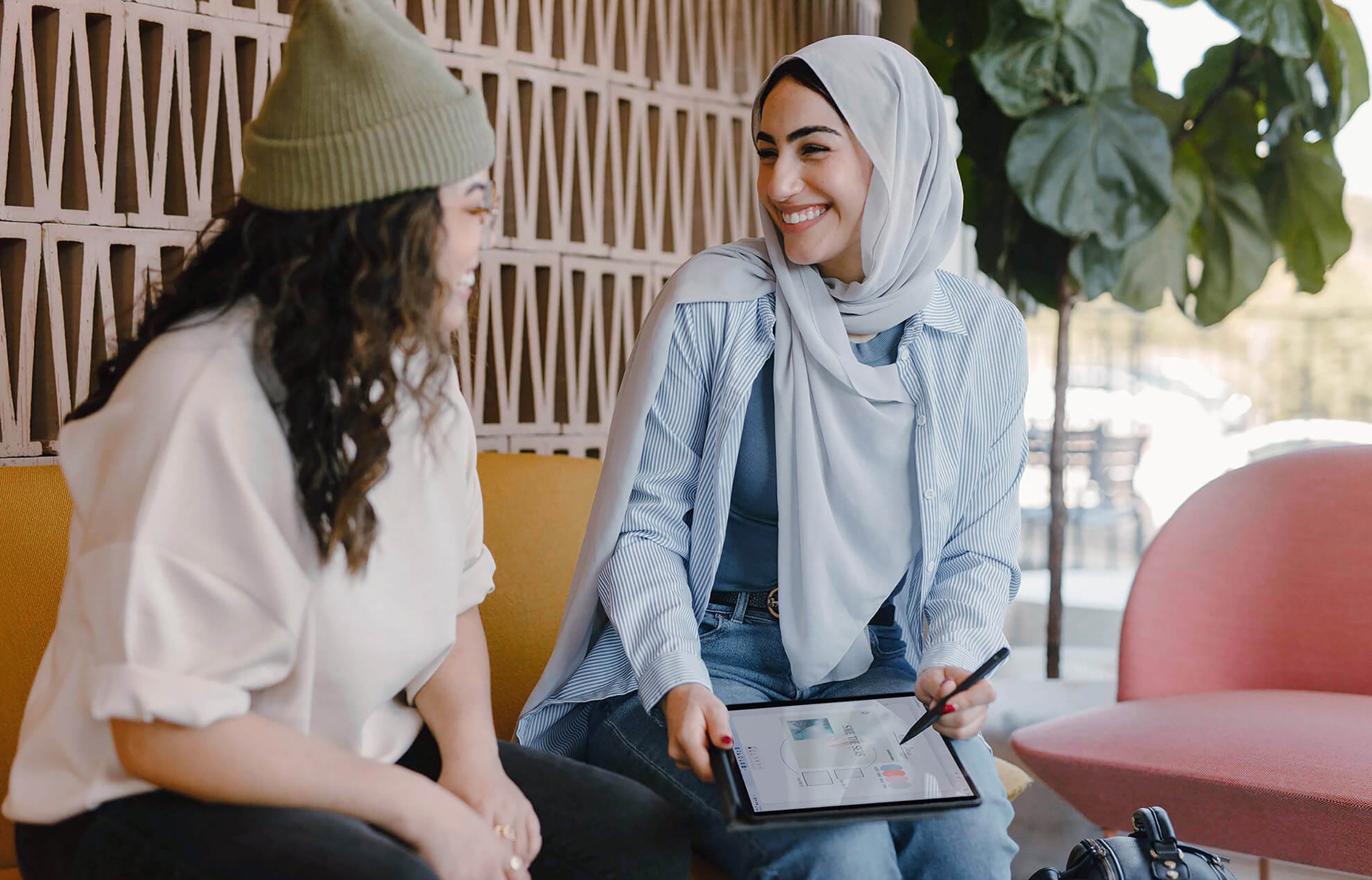 Two women discussing ideas while reviewing work on a tablet