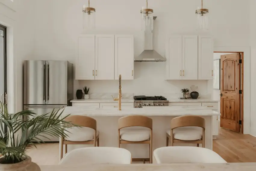Modern white kitchen with stainless steel appliances and island.