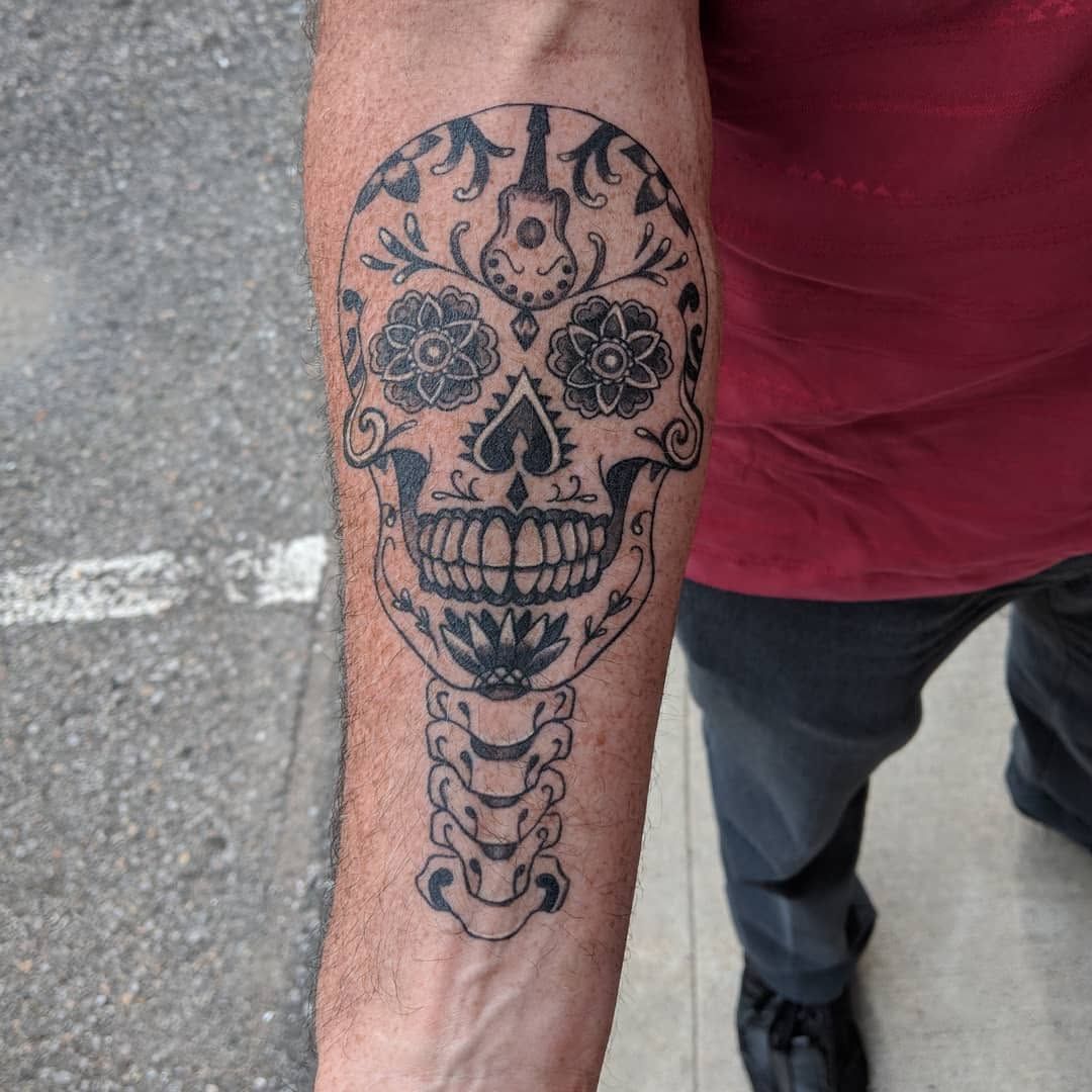 Black-and-grey sugar skull sleeve tattoo on an arm