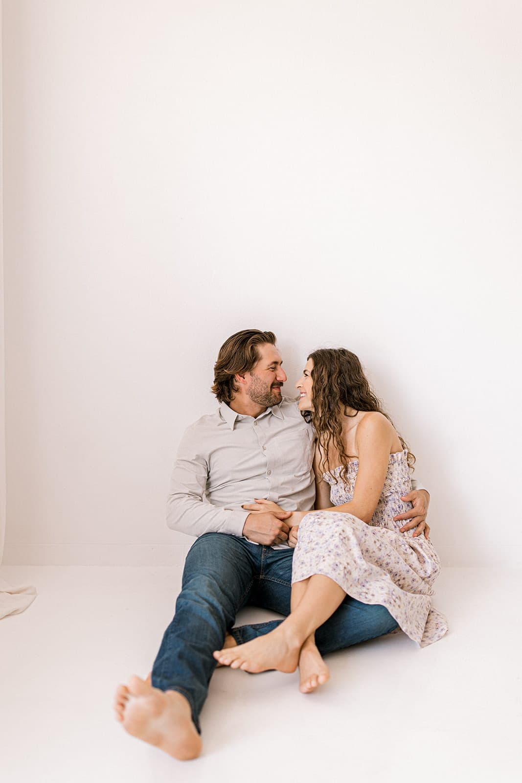 The couple shares a warm moment sitting on the floor, smiling and looking into each other’s eyes at Revelator Studio in Shreveport.