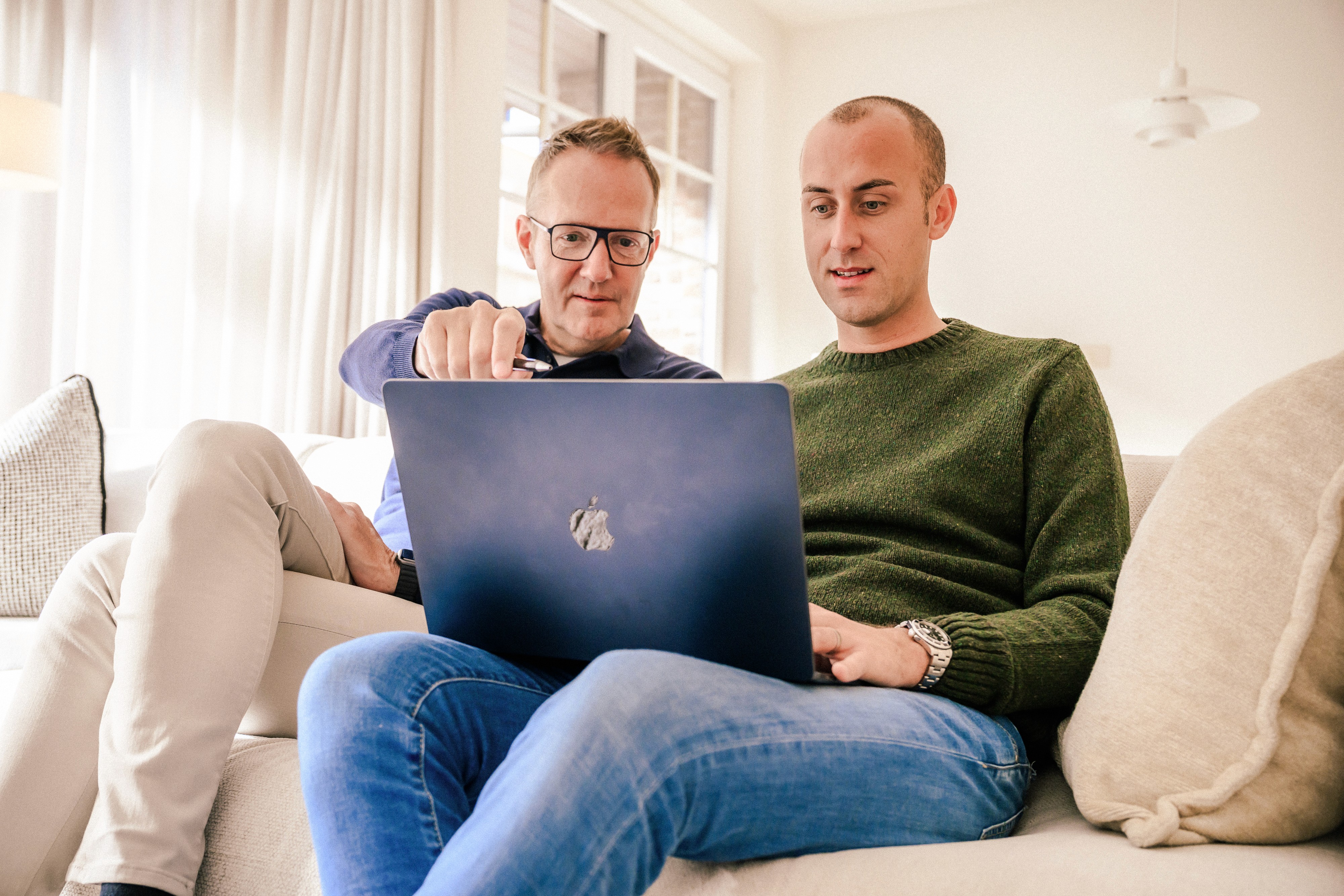 Hans en Johan in de sofa, Hans wijst iets aan op de laptop van Johan