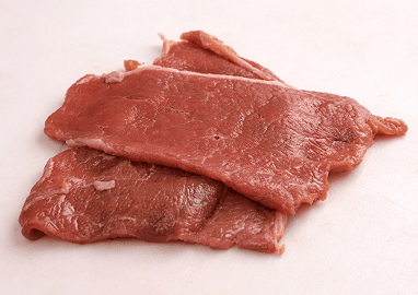 A rustic outdoor market stall displays an array of fresh produce including vibrant tomatoes, leafy greens, and a variety of olives, set against the backdrop of a picturesque rural Italian village.