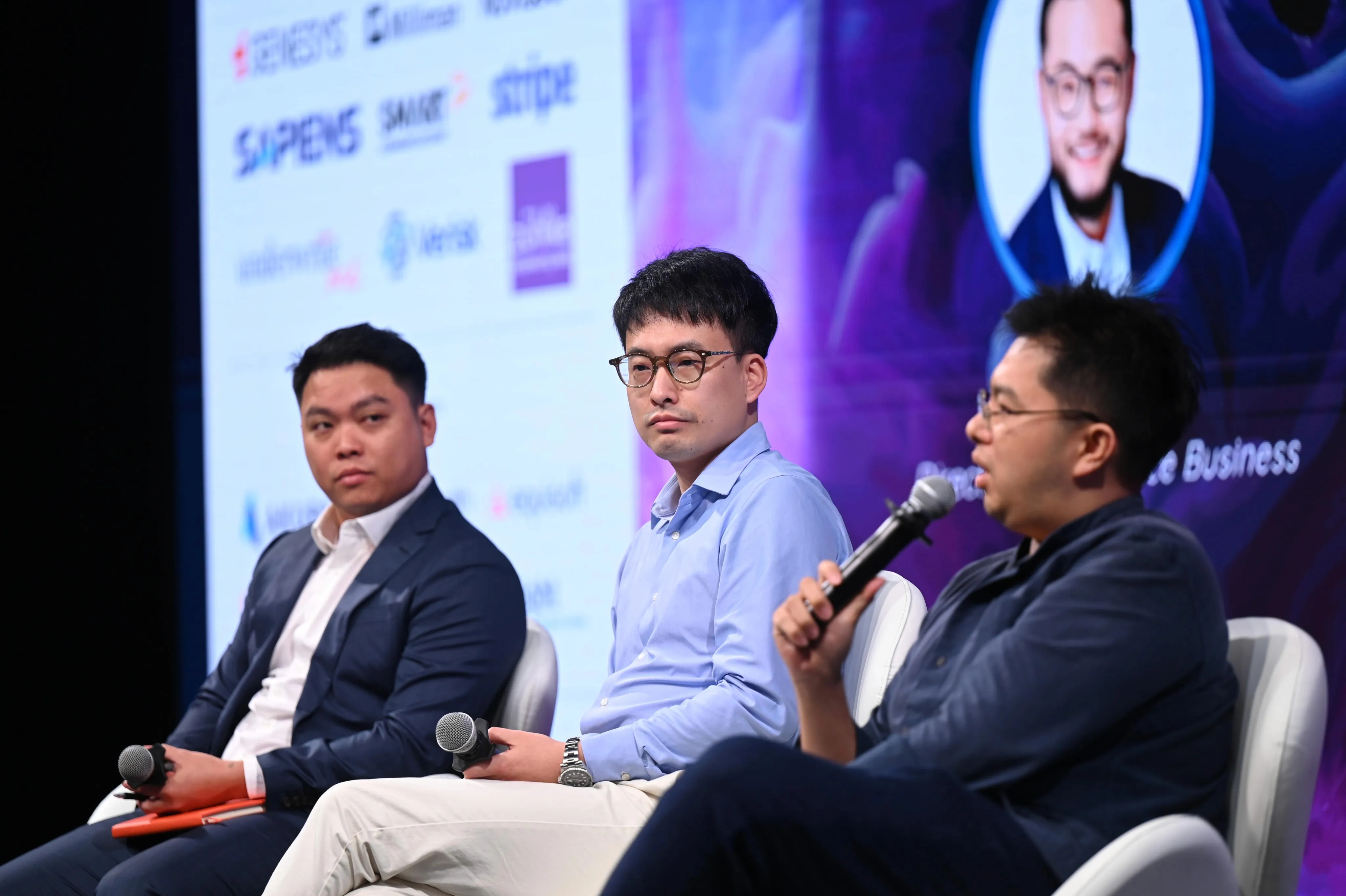 Panel discussion with three speakers seated; one is speaking while the others listen attentively.