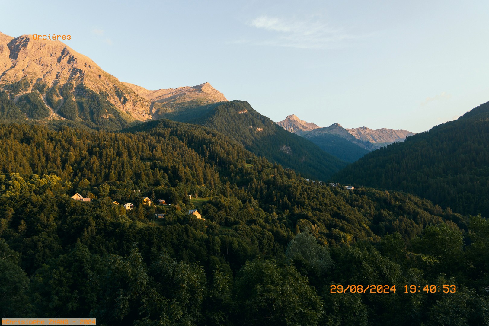 Paysage alpin au coucher du soleil, mélangeant forêts denses et sommets rocheux à Orcières.