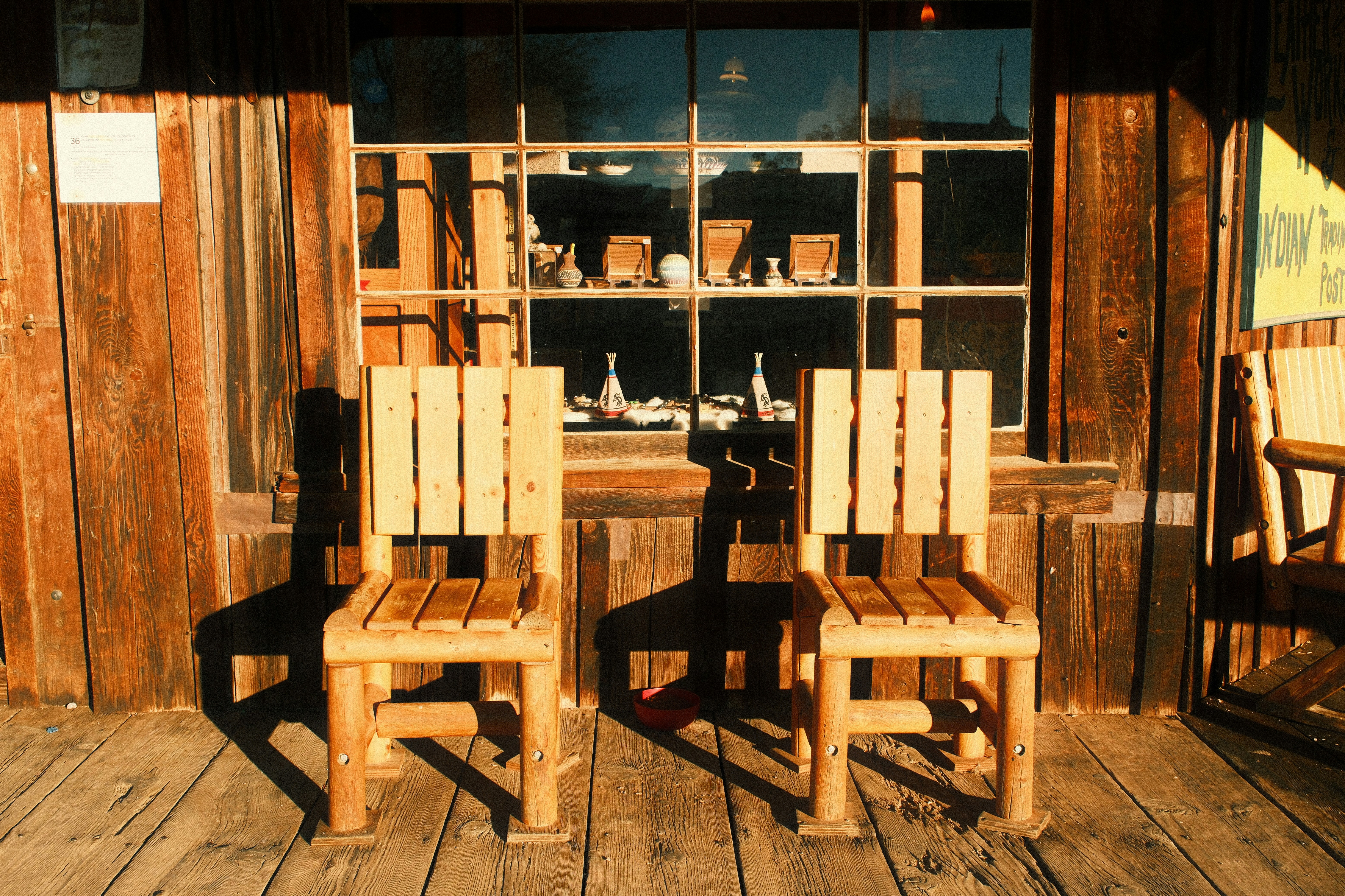 Two wooden chairs on a rustic porch.