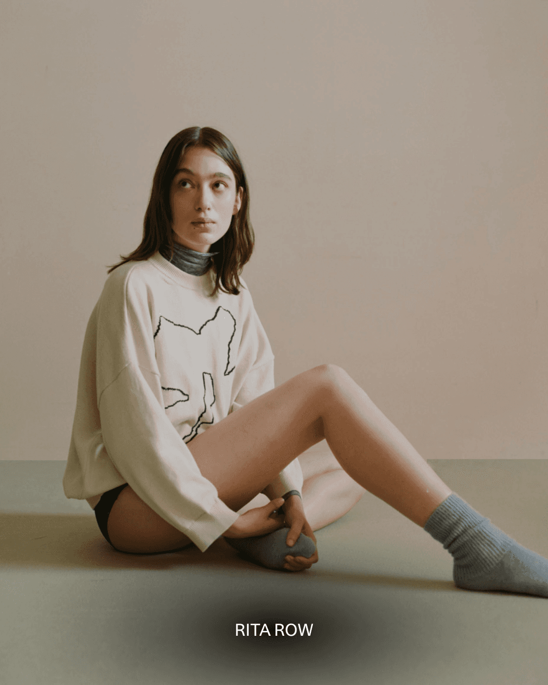 Dans le lookbook Rita Row, une mannequin porte un pull blanc avec un motif de grosse fleur