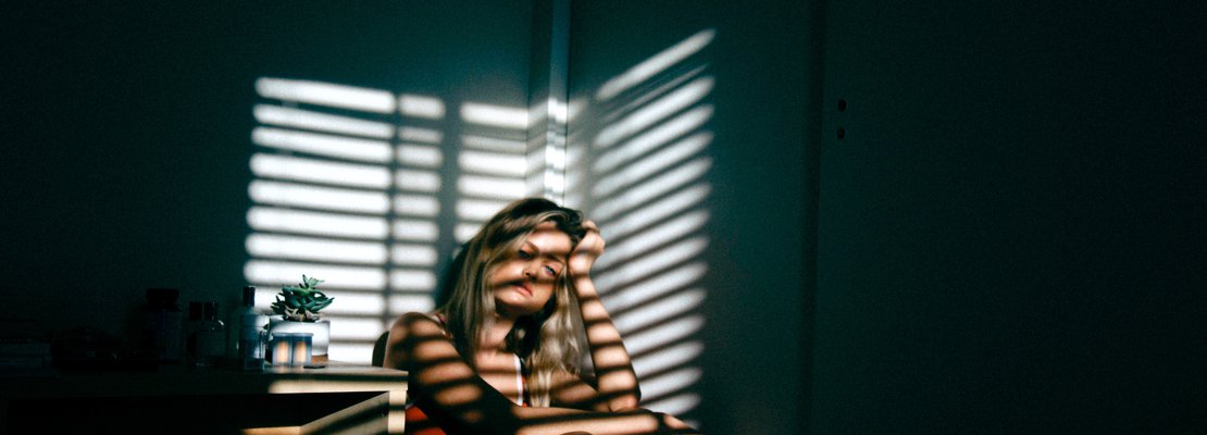 A woman inside a room facing lights from the window