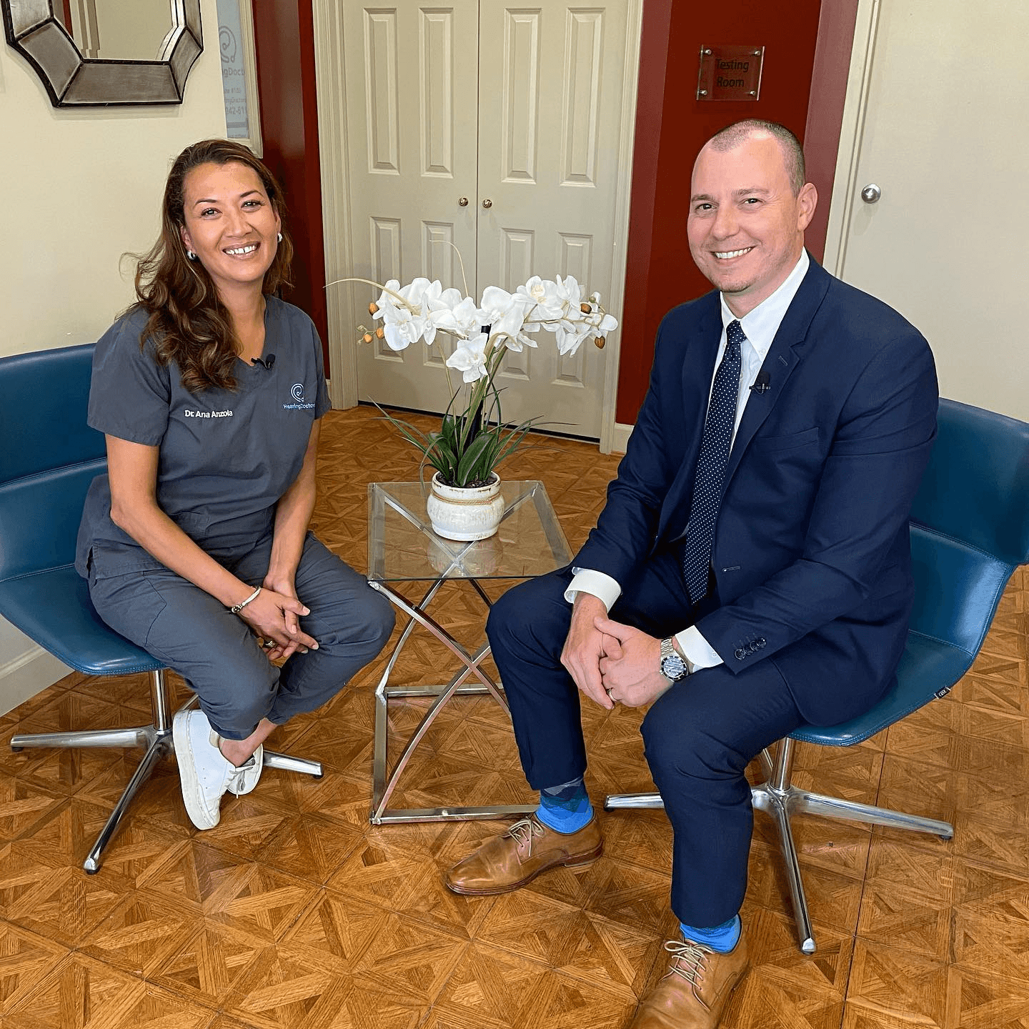 A person sits with their hands on their head, appearing stressed or in deep thought. Background is blurred.
