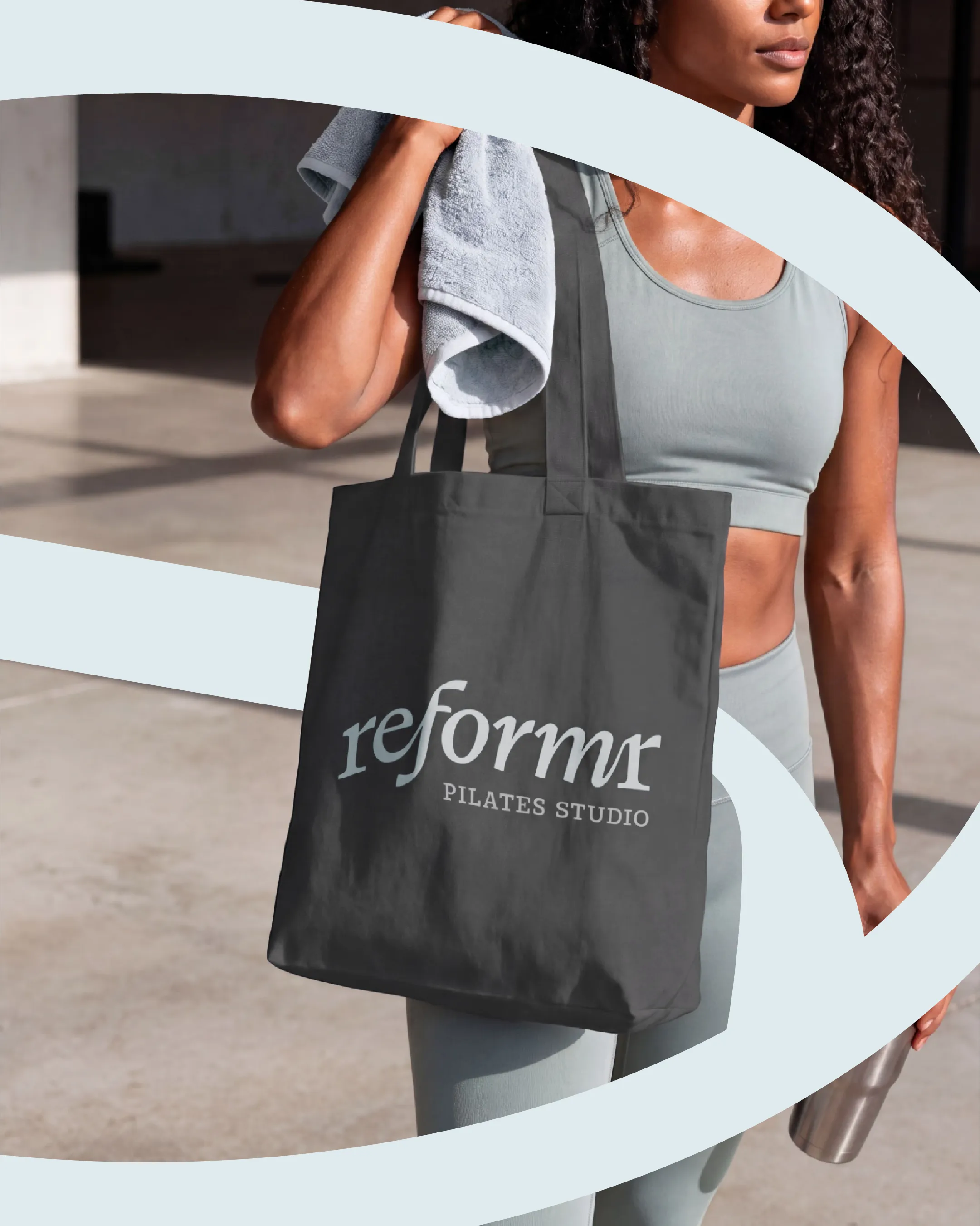 model carrying dark branded tote bag with Reformr Pilates Studio wordmark