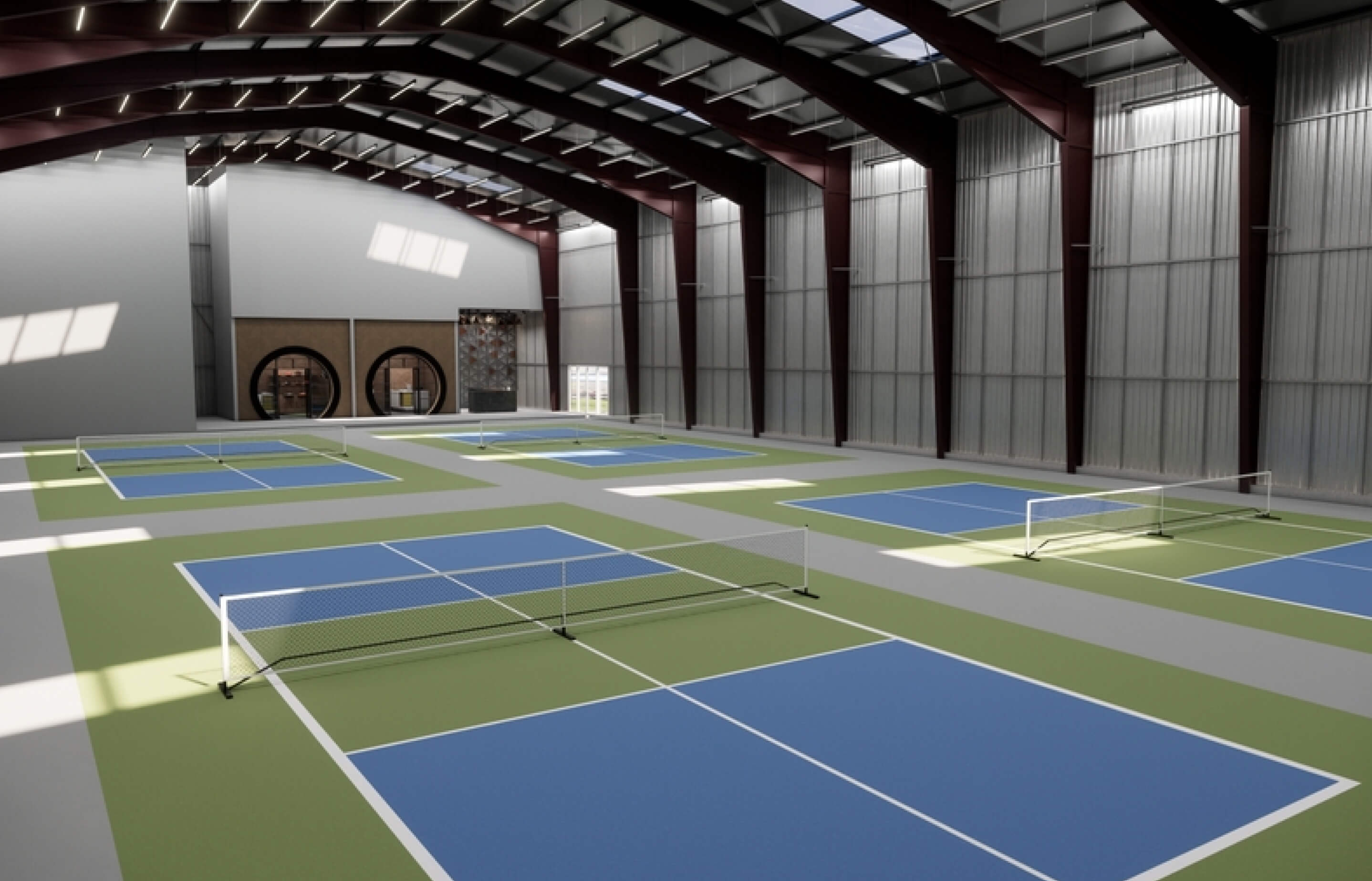 Indoor tennis facility featuring multiple blue courts and high ceilings, with a modern design and spacious layout.