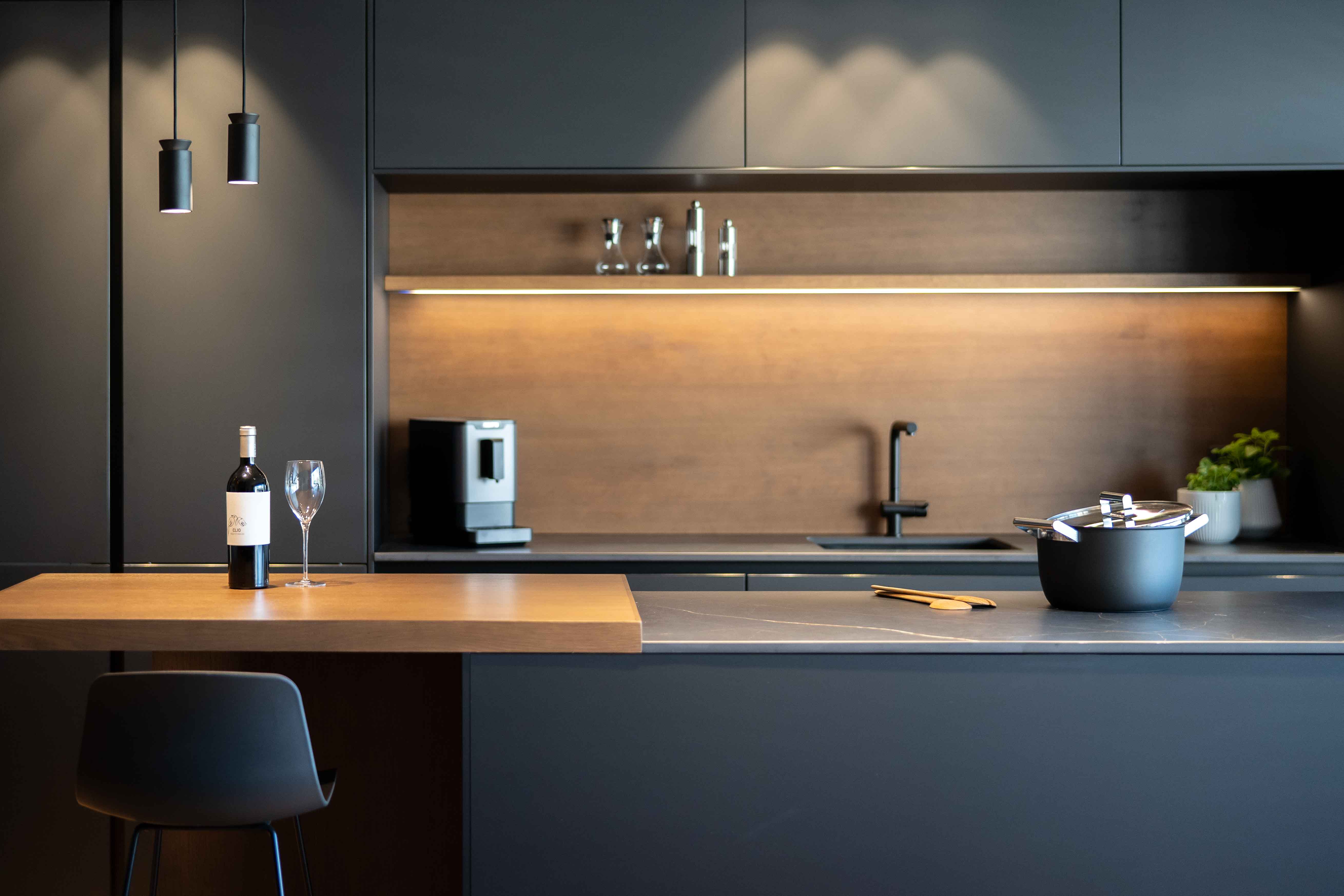 Detalle de cocina-comedor abierta de estilo oscuro con muebles y encimera de acabados negros