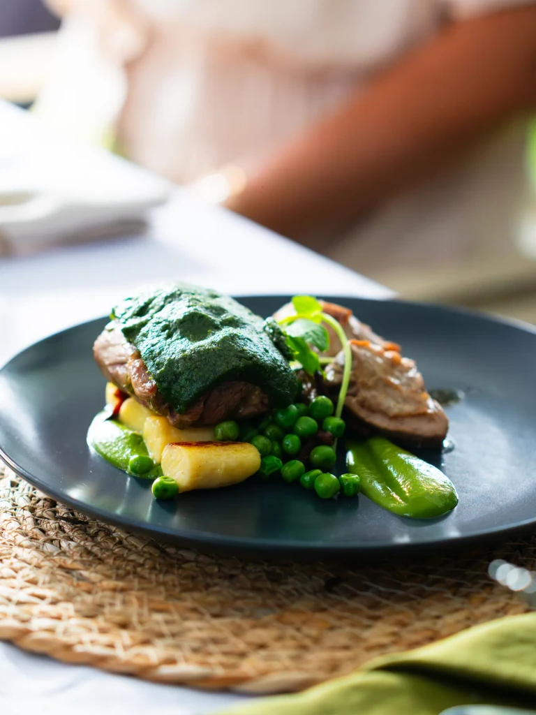 Herdwick lamb plated on dark stoneware on a woven placemat