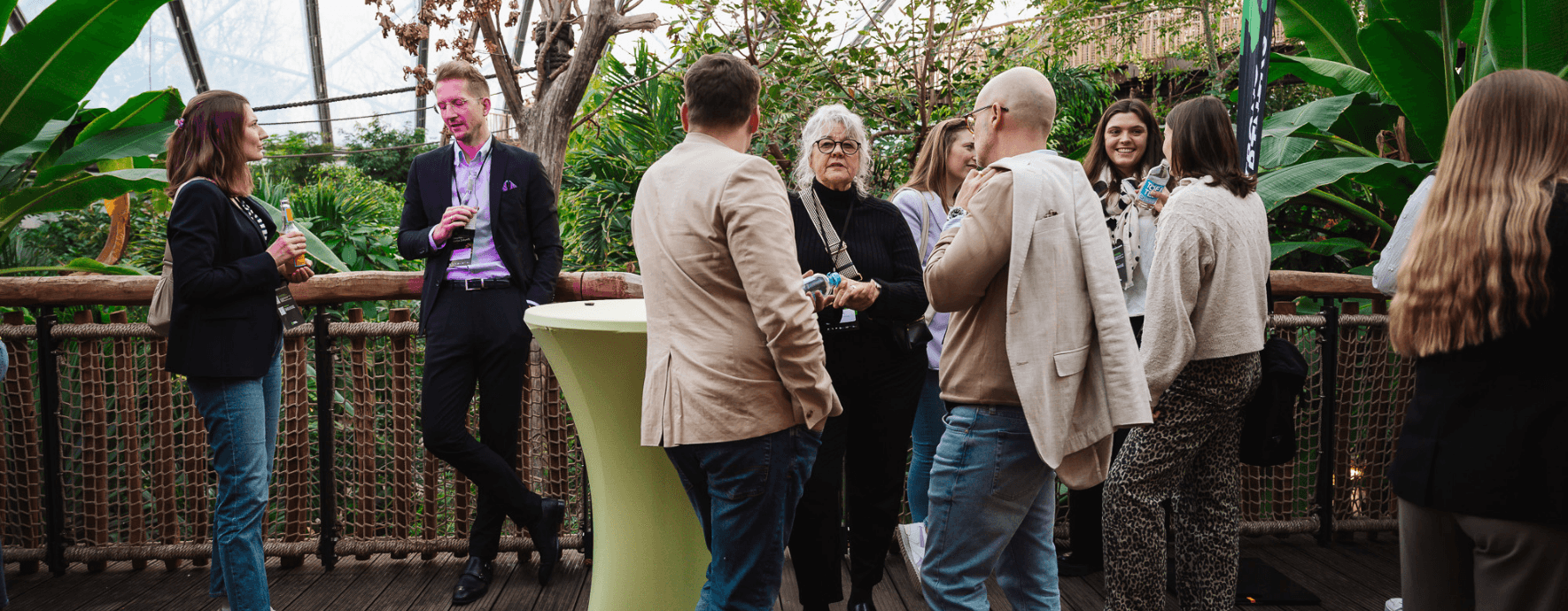 Menschen beim Netzwerken an Stehtischen in der Meranti-Halle des Allwetterzoos Münster