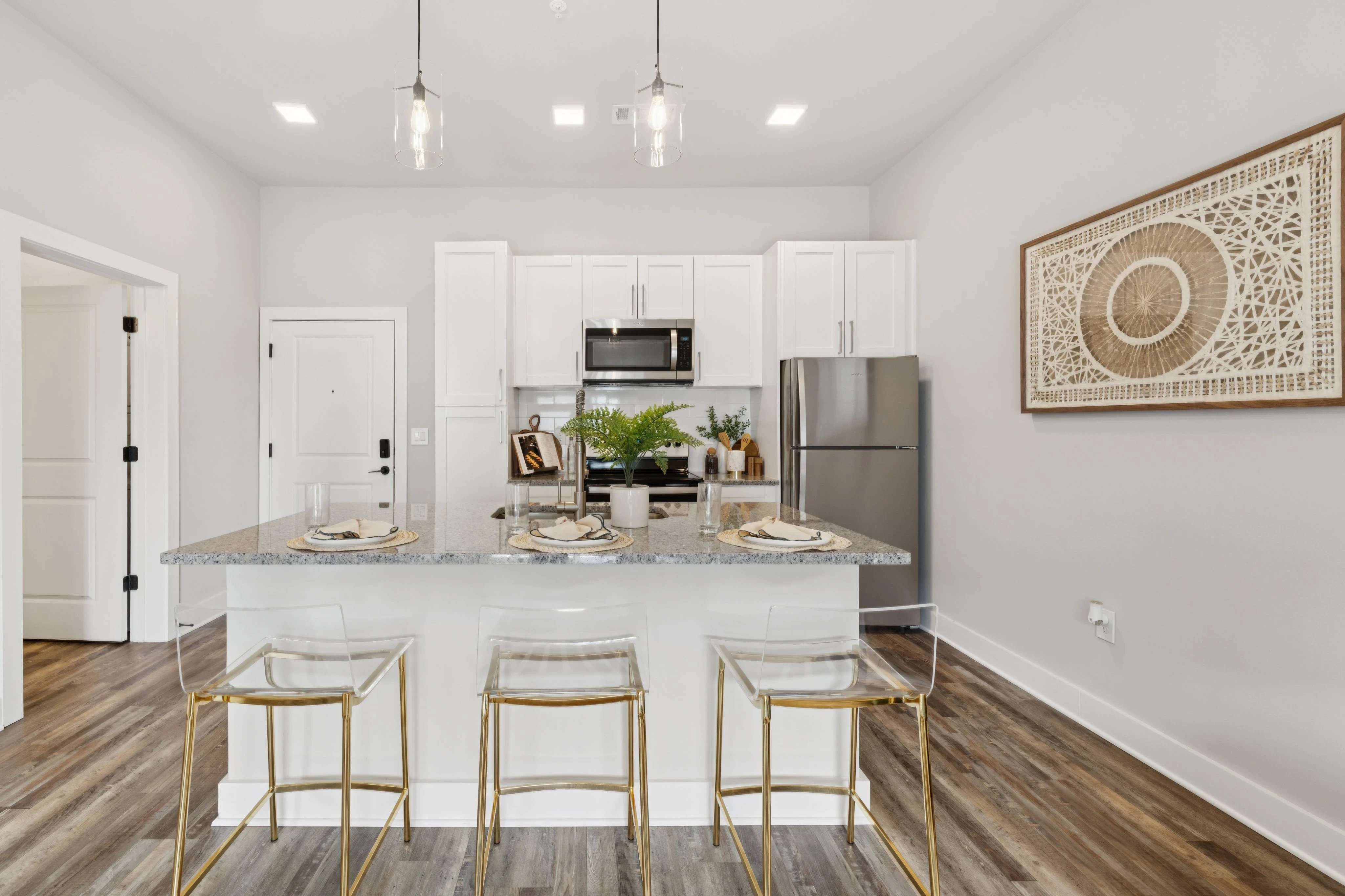 A bright kitchen with white cabinetry and a stylish bar stool positioned at the counter.