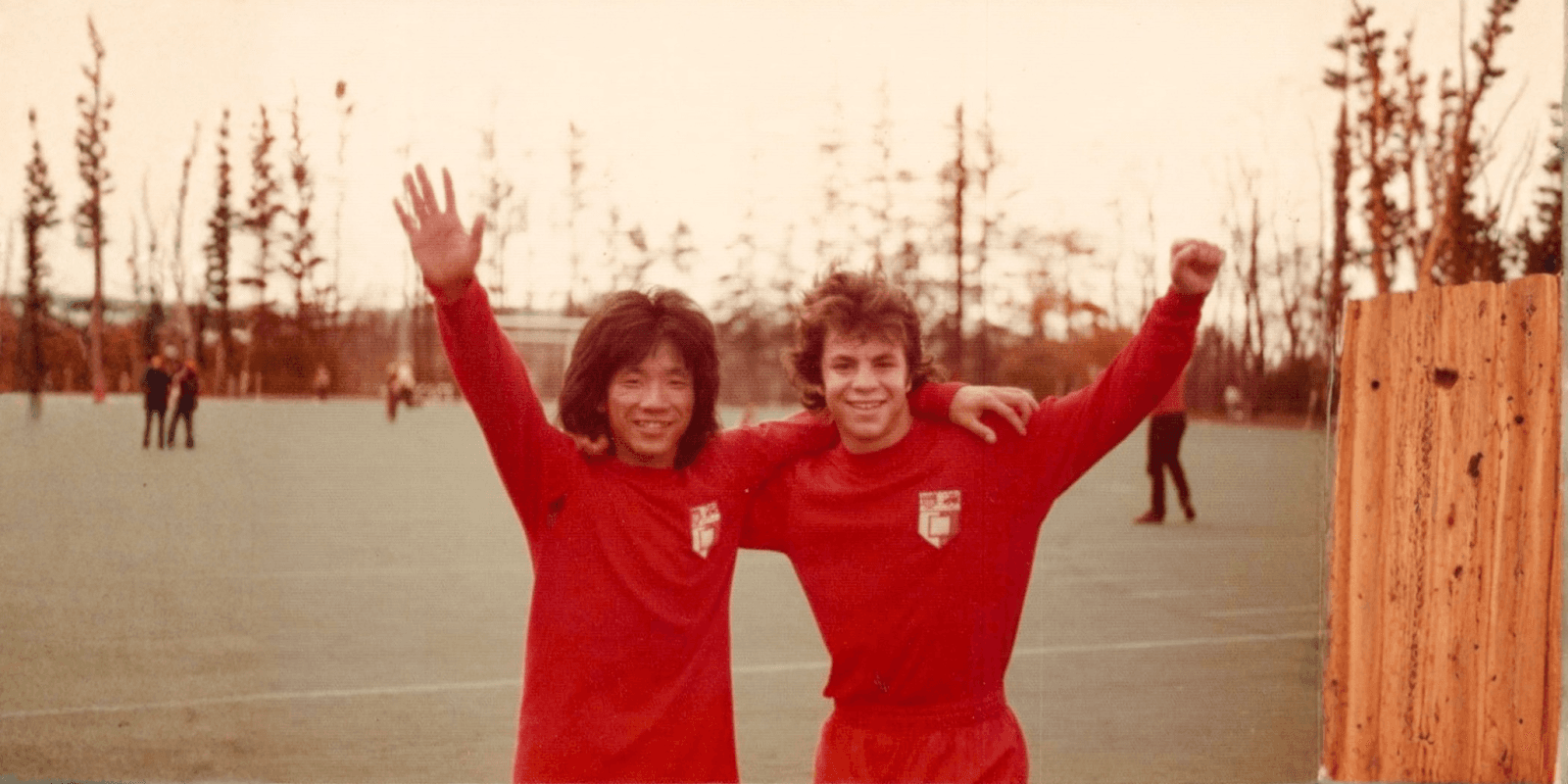 Joe Mui and teammate at soccer field, celebrating a moment of triumph.