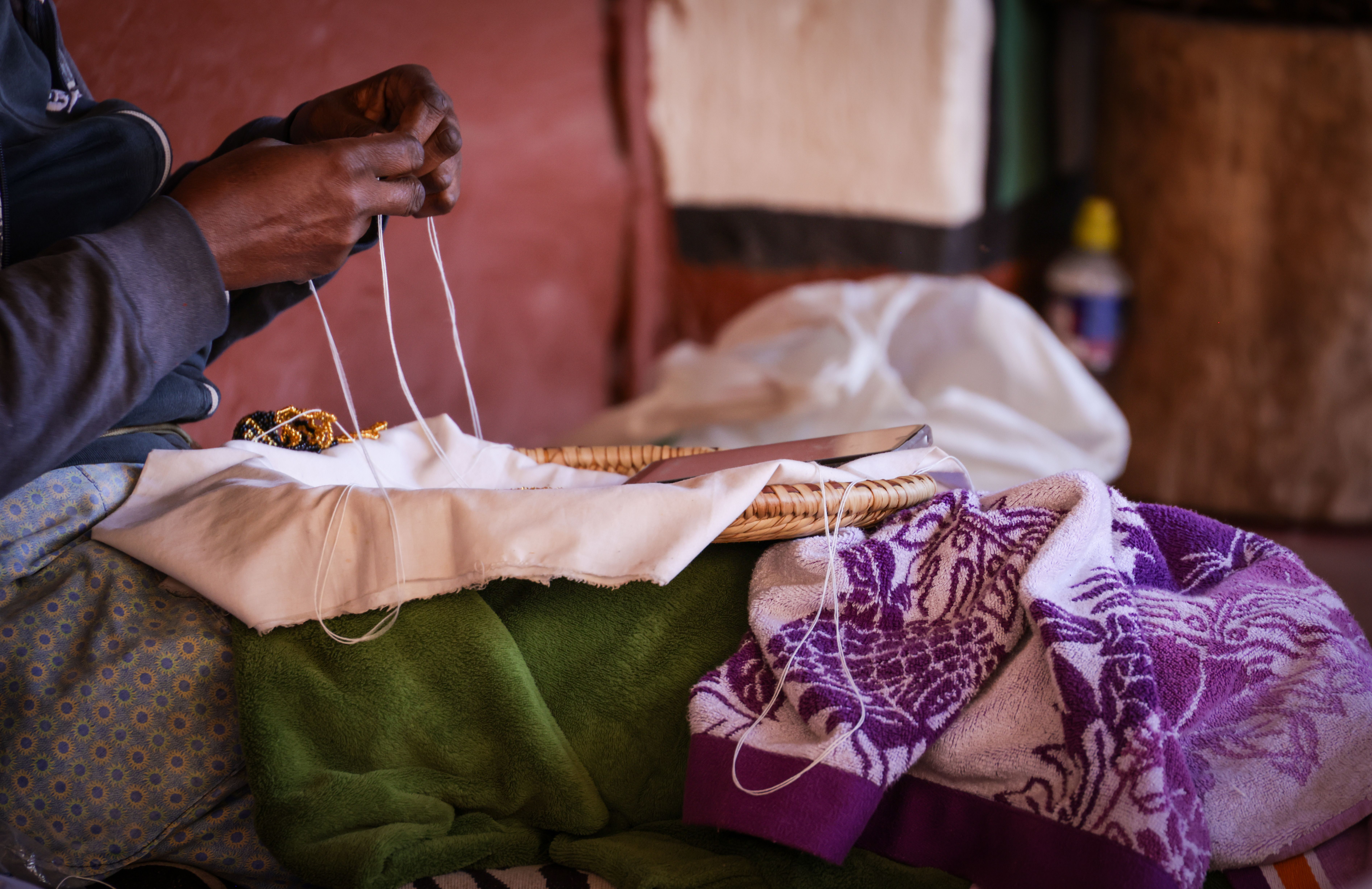 Artisan crafting intricate beaded designs indoors, emphasizing traditional handcraft skills. Magda Ehlers. 