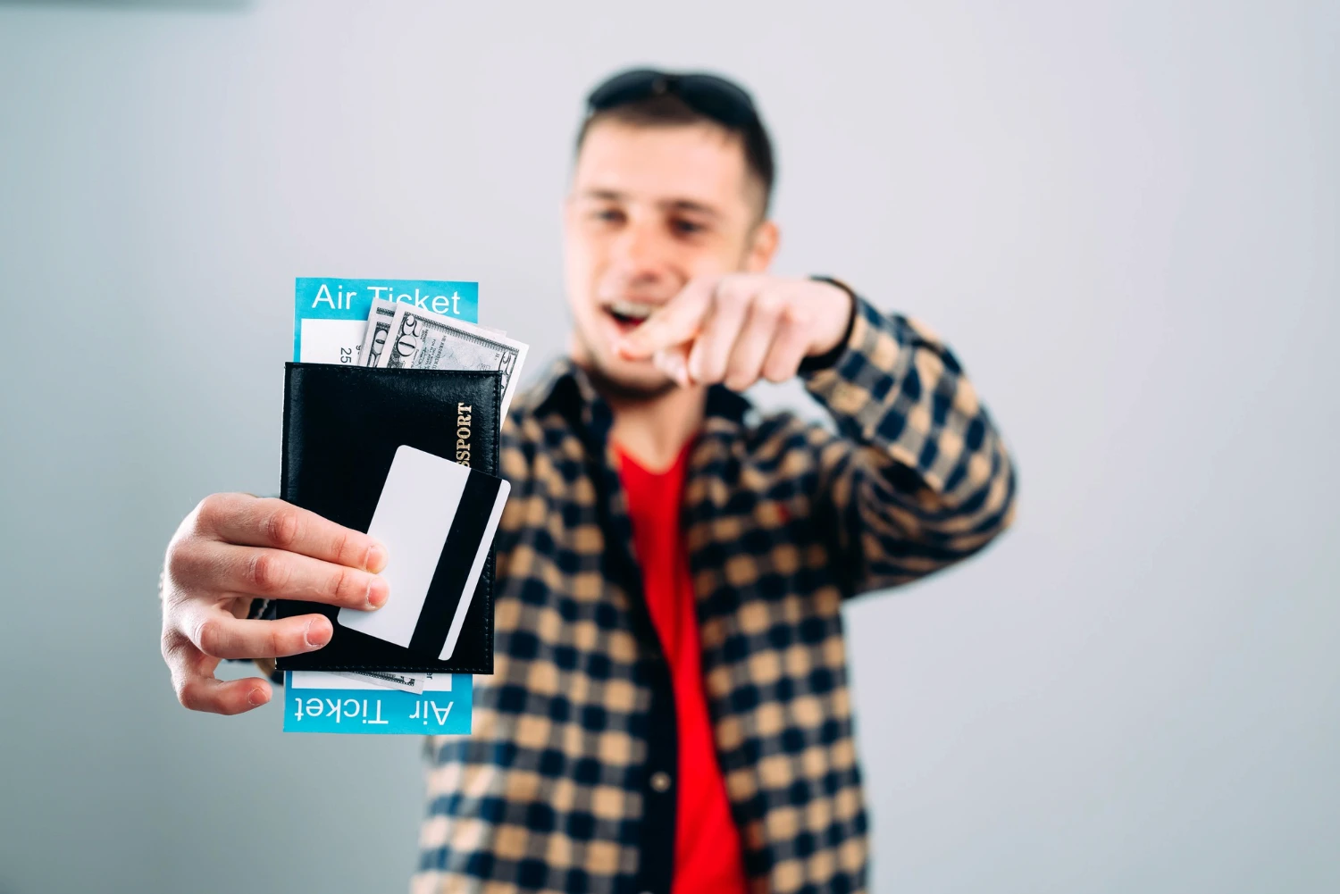 A man holds a plane ticket and money in his passport