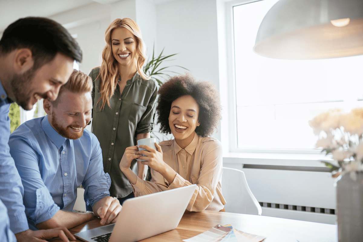 cross functional team: Colleagues smiling while looking at their teammate's laptop screen