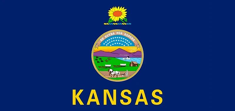 The Kansas state flag features a blue background with the state seal centered below a sunflower. "KANSAS" is written in bold yellow letters beneath.