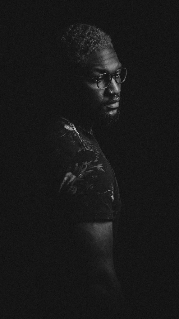 black white image of a male model looking away from the camera wearing a shirt with flower pattern and a pair of glasses.