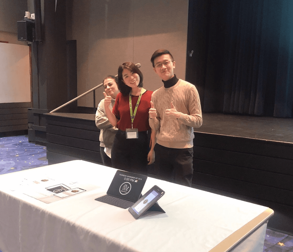 Modern home office setup with a monitor, ergonomic chair, keyboard, and indoor plants near a window with blinds.