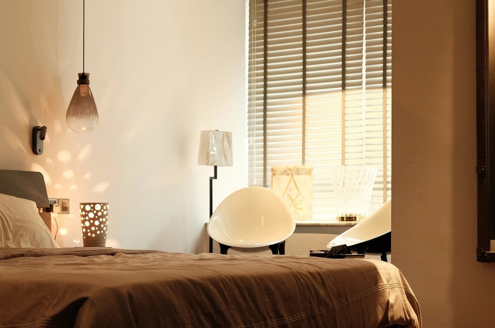 Warm, minimalist bedroom with natural light, wooden accents, and cozy lighting by Persqft interior design