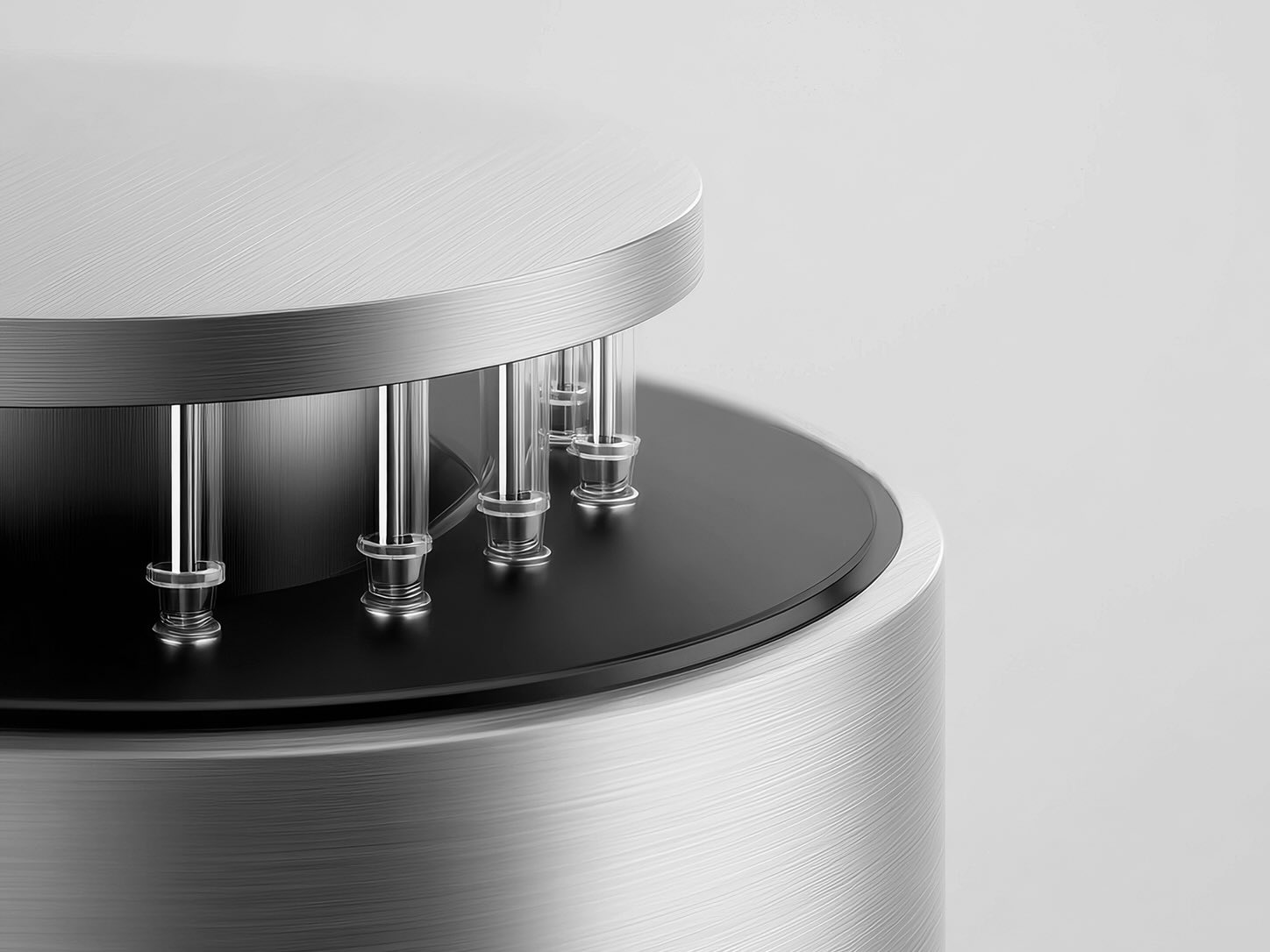 Monochrome close-up of a sleek circular metal device with polished vertical rods mounted between its upper and lower platforms.