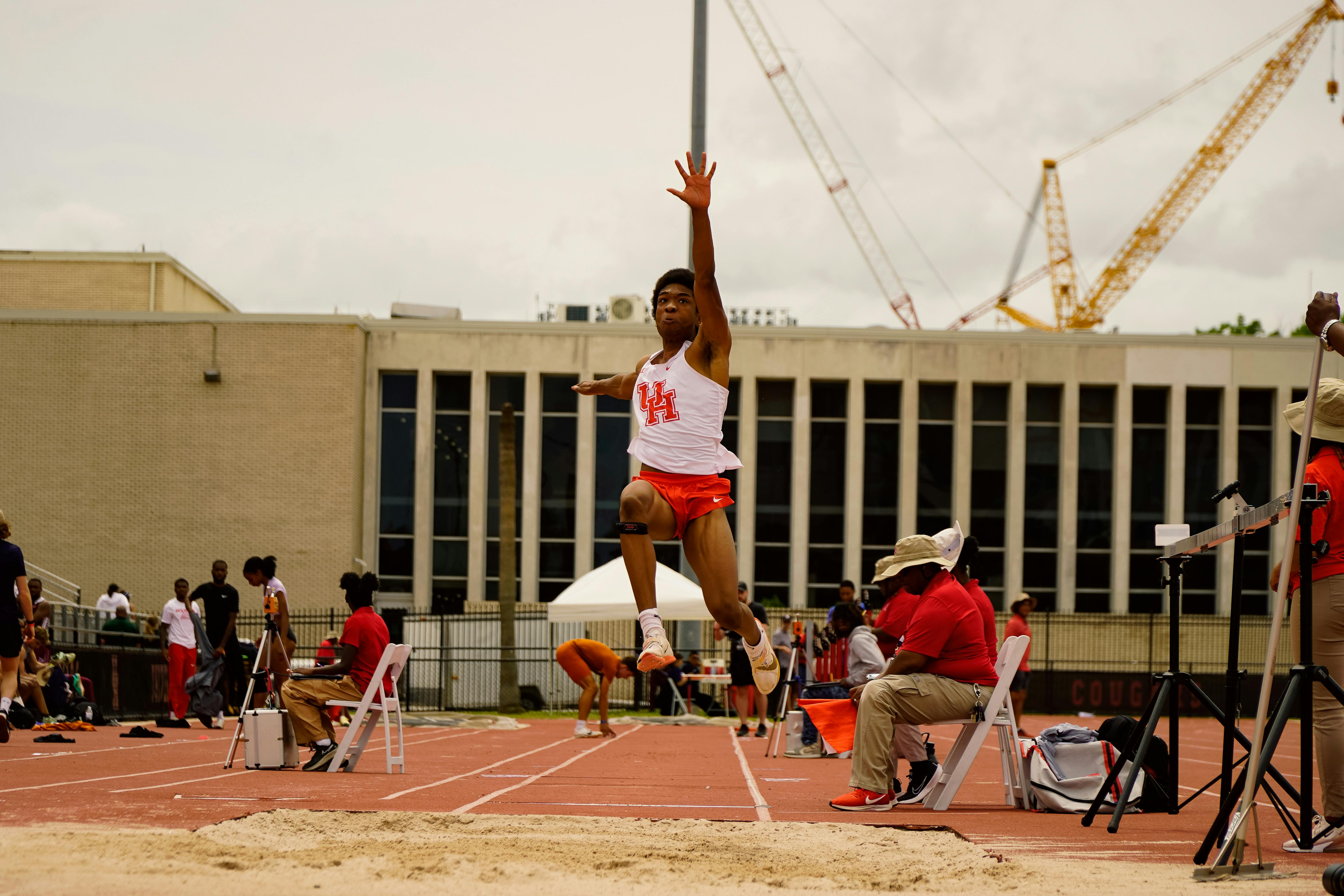 College age Black male doing the long jump on the field