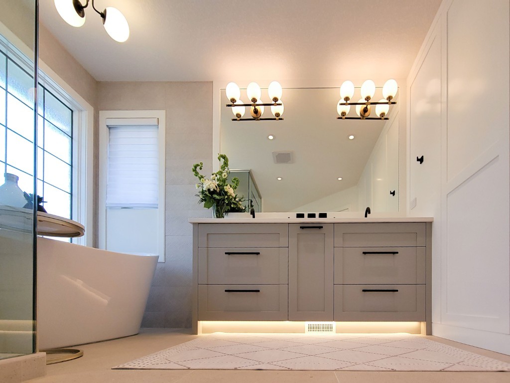 Image of Modern primary ensuite bathroom interior with gray cabinetry, large mirror, and freestanding tub by KHD Homes.